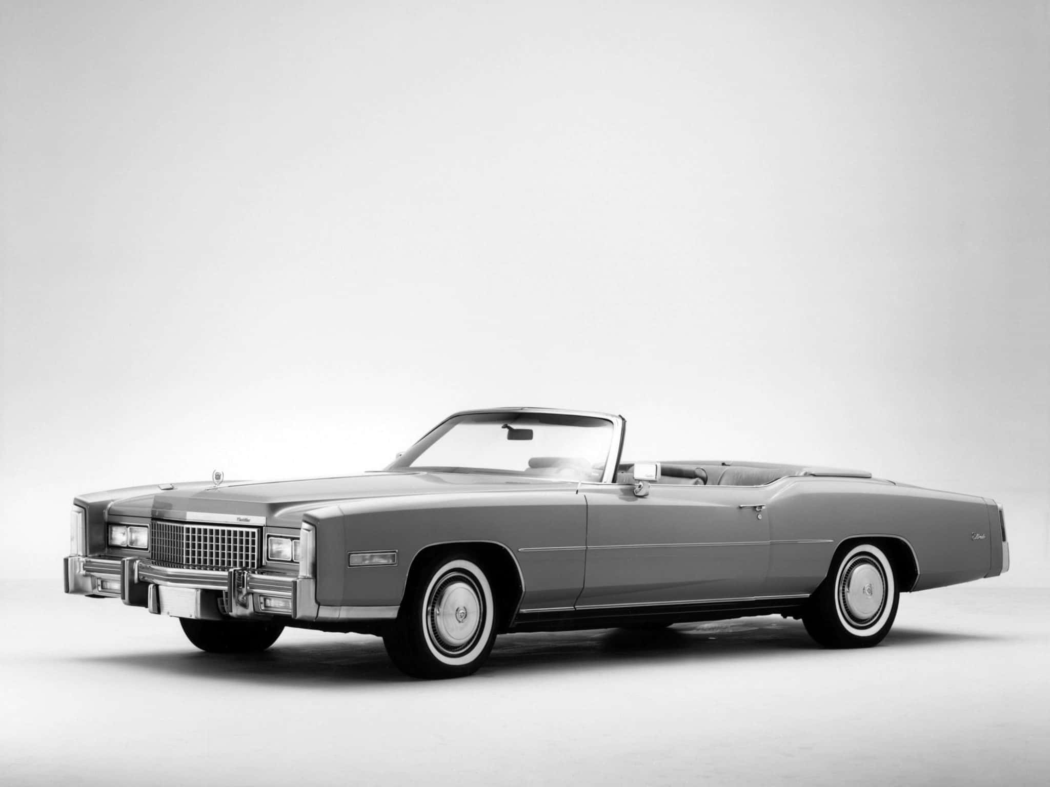 Cadillac Fleetwood 桌布 壁紙 — 一輛經典的銀色敞篷車，帶有鍍鉻細節和白邊輪胎，擺放在簡潔的攝影棚背景前。