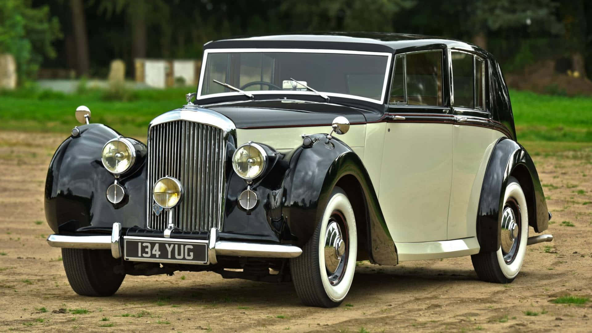 Bentley Mark Vi 桌布 壁紙 — 一輛經典雙色復古車，帶有鍍鉻裝飾和白色輪胎，停在泥地上。