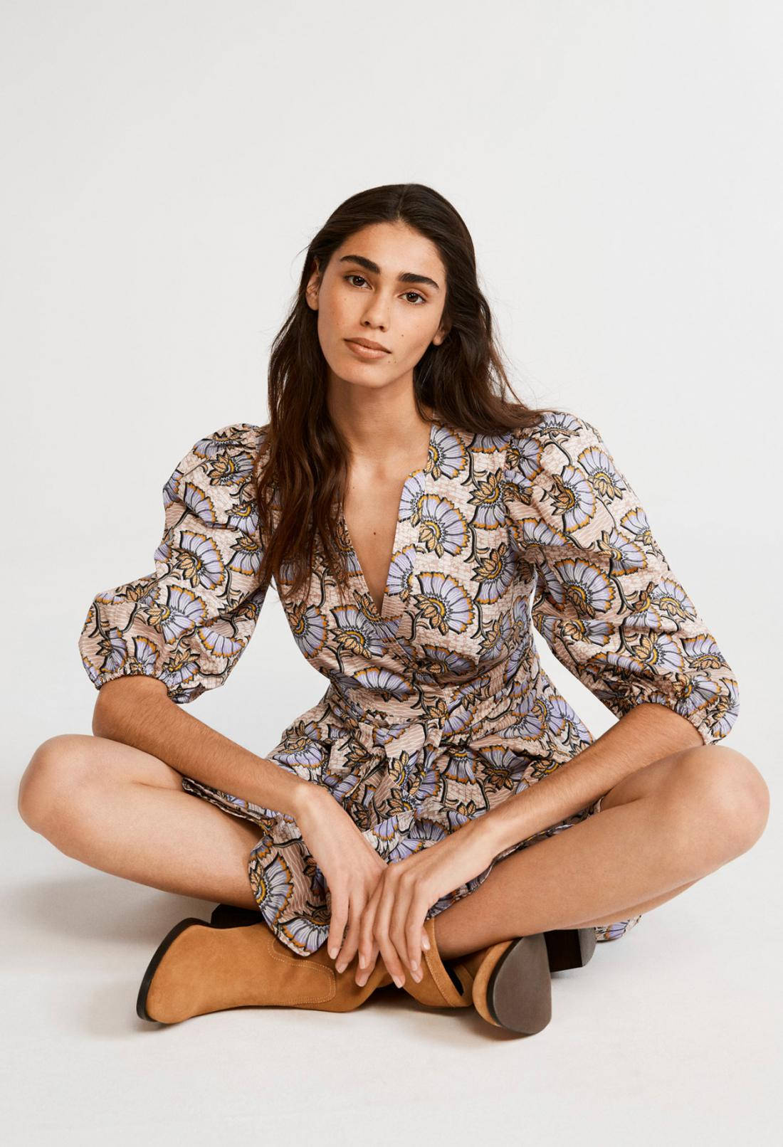 Claudie Pierlot裹身裙配蓬袖 壁紙 — 一名女性穿著花卉圖案連衣裙，在純白色背景前盤腿而坐。