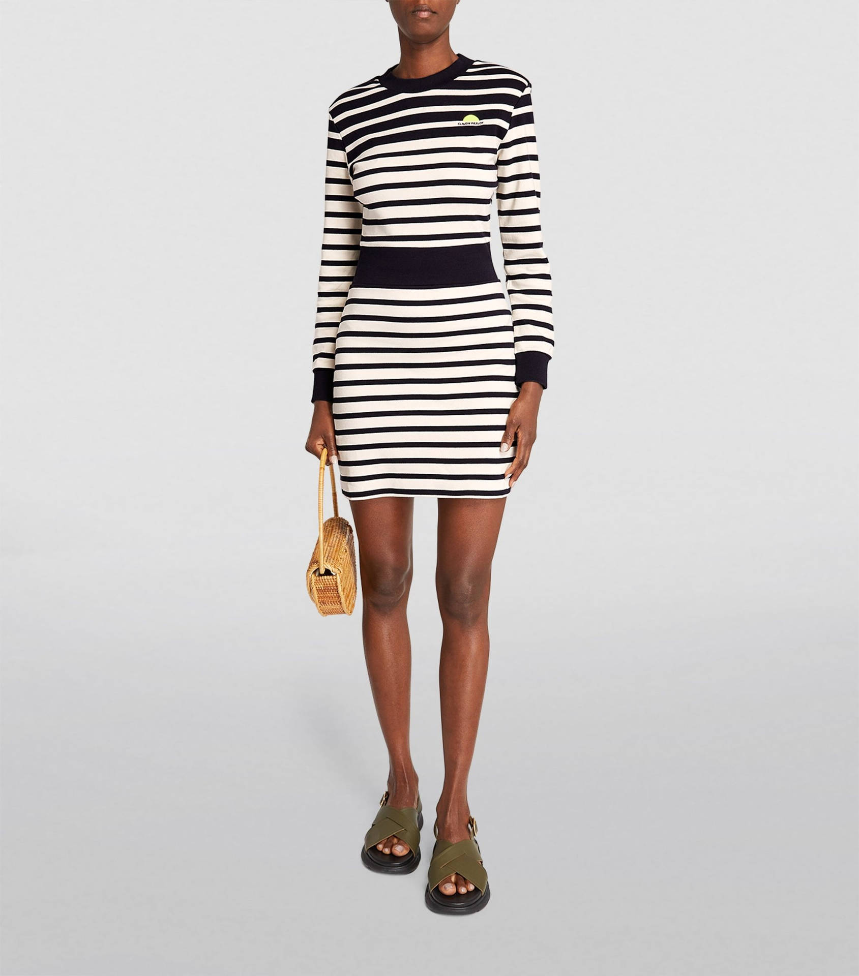 身穿條紋裙的女士手持編織袋，穿著涼鞋
