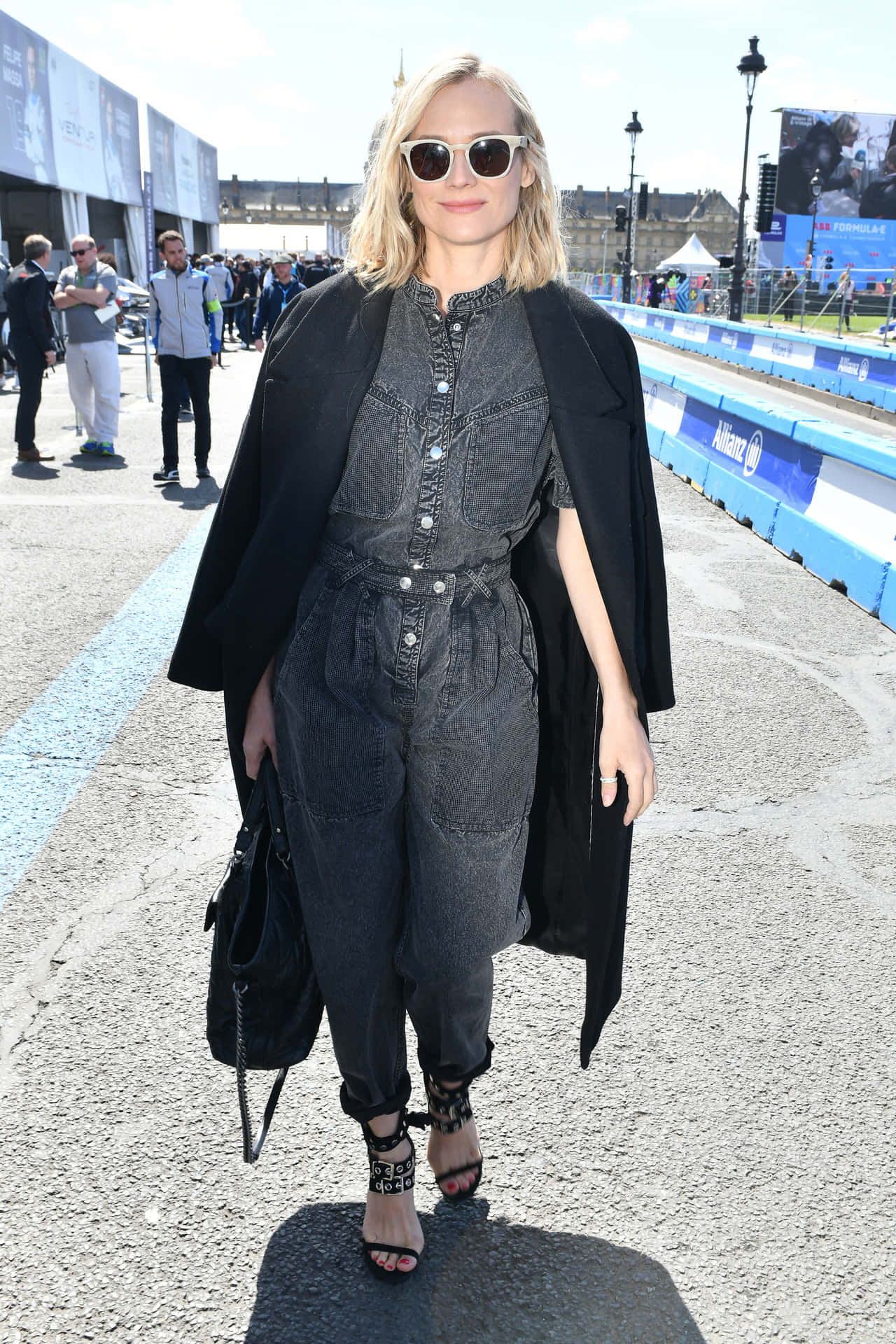 金髮女子戴著太陽眼鏡，身穿牛仔服裝，在賽道上行走。