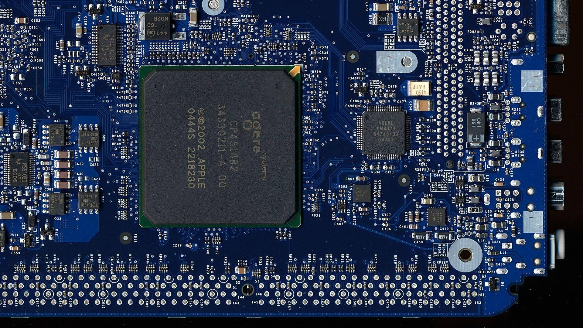 開關與繼電器電路板 壁紙 — 藍色電路板嘅特寫，中央有一個 Apple CPU 晶片，周圍係複雜嘅電子元件。