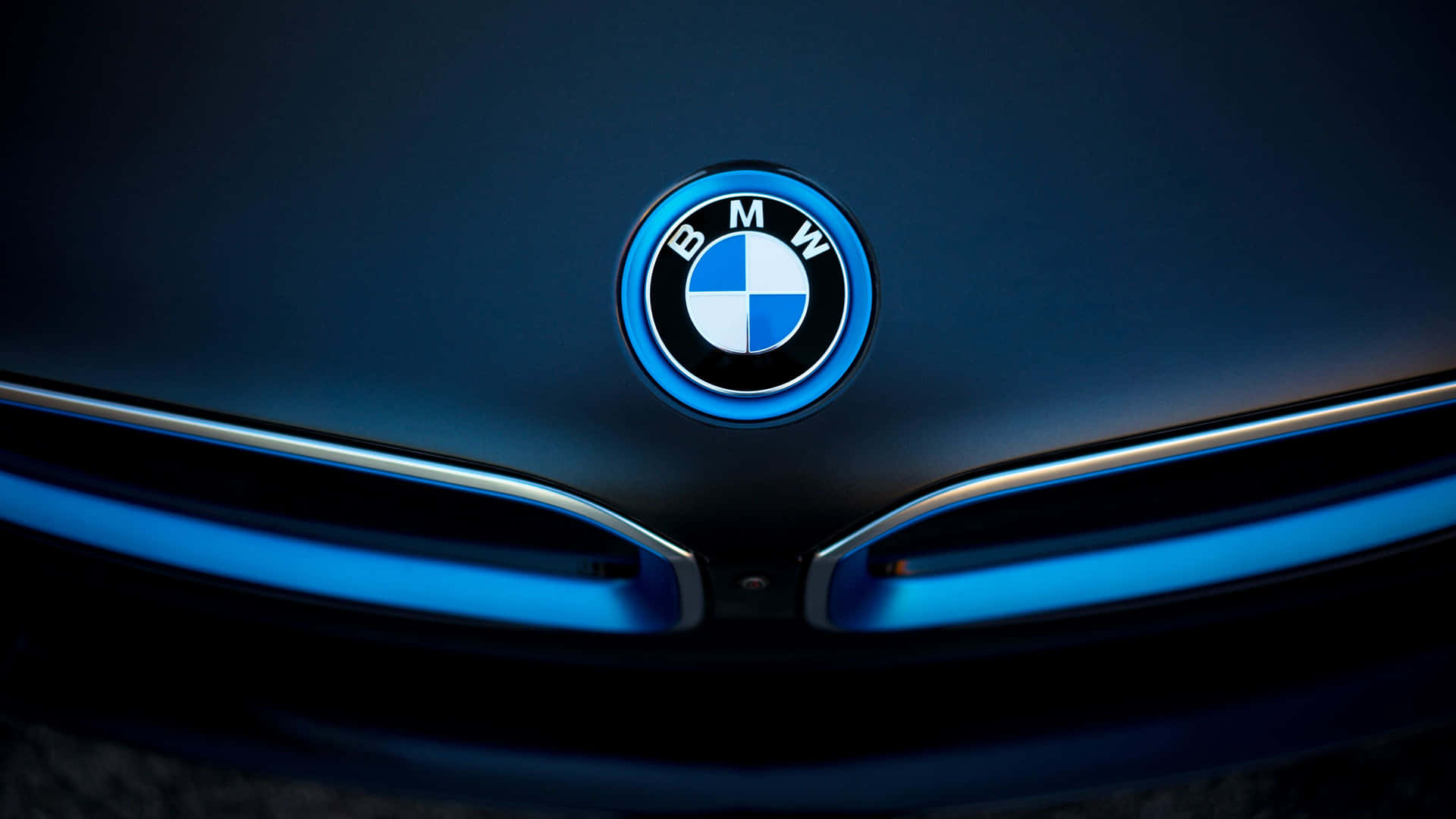 BMW 標誌在深色車頭蓋上以藍色照亮，配以時尚頭燈。