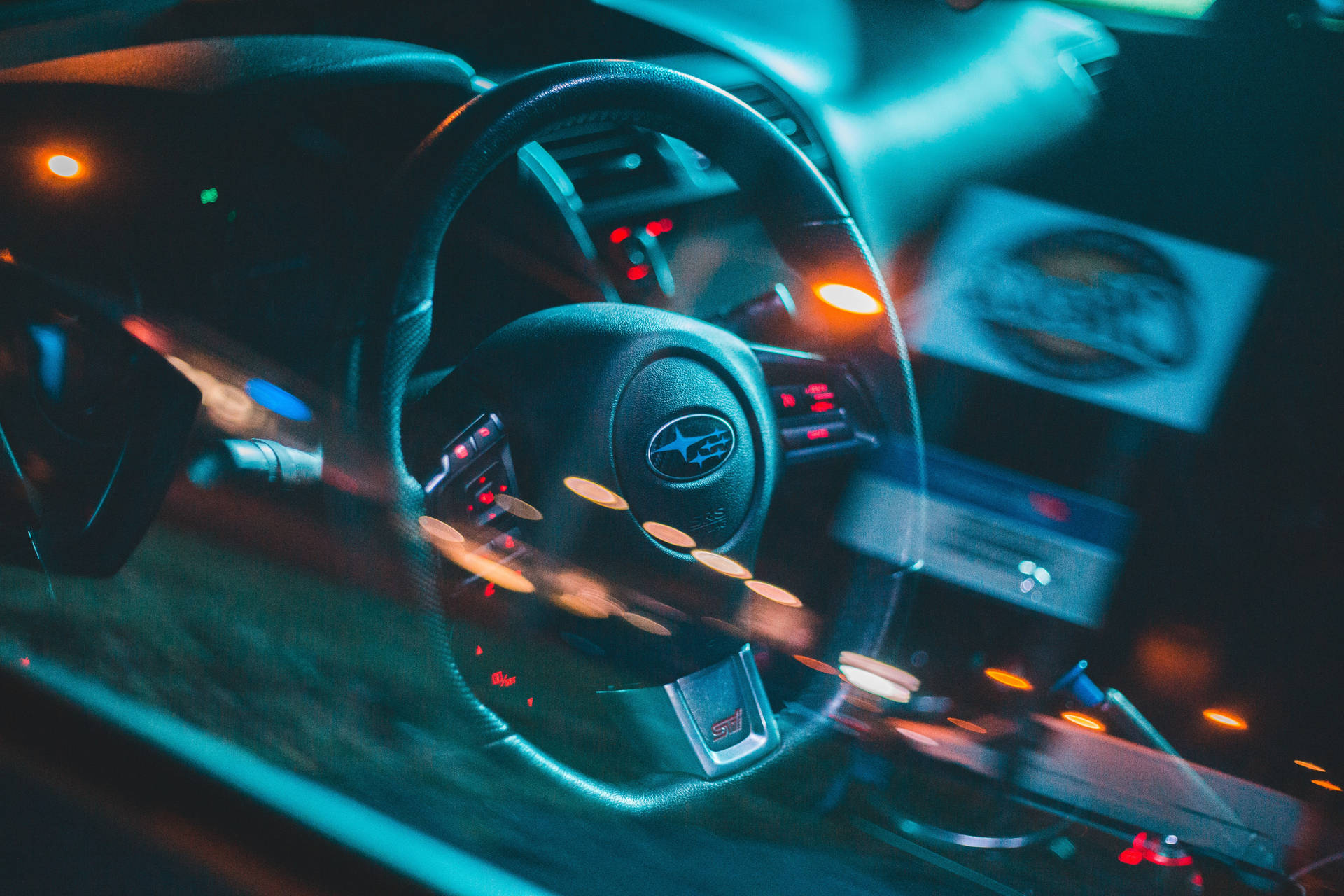 夜間被霓虹藍和橙色光照亮的汽車方向盤。