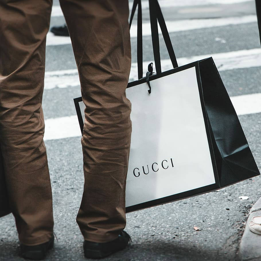 人在城市人行道上拿著Gucci購物袋行走