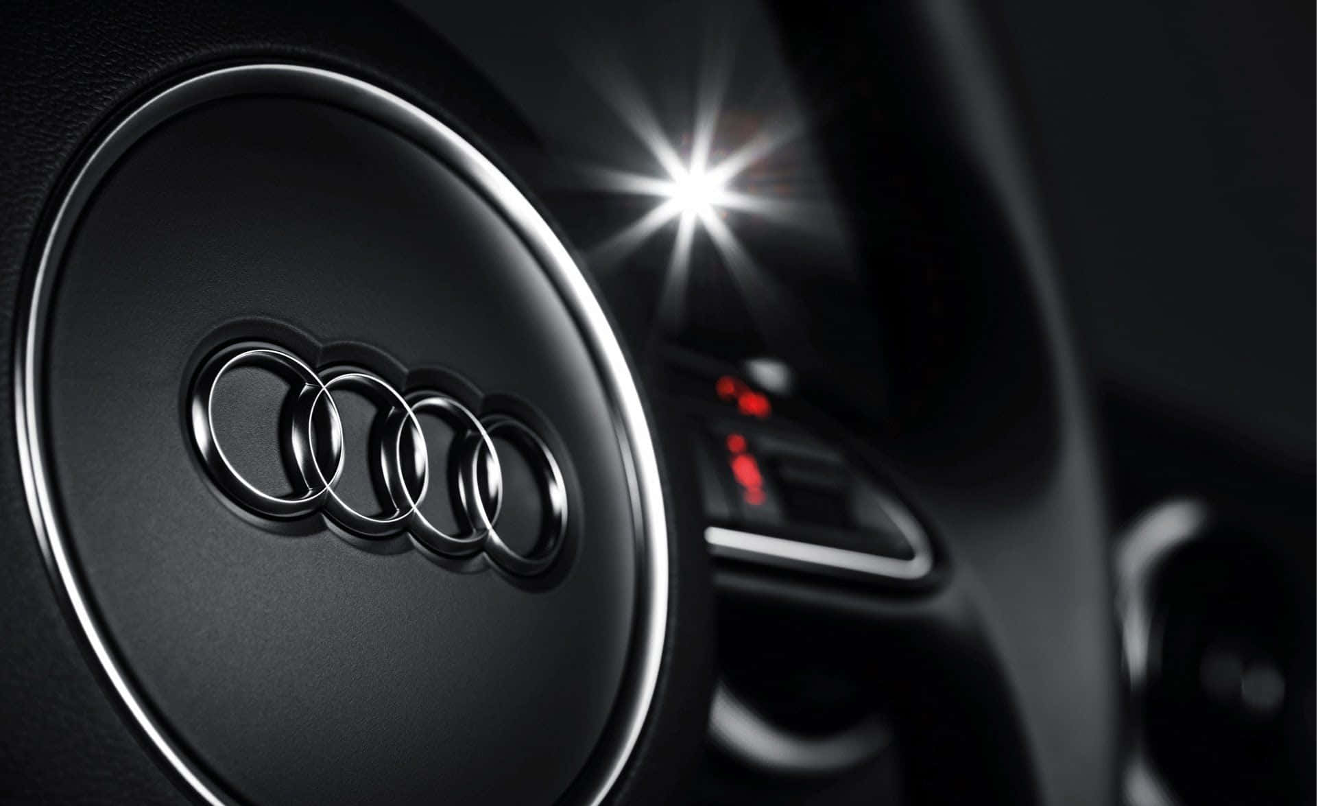 Audi S3 桌布 壁紙 — 黑色奧迪方向盤特寫，帶有鍍鉻環和背景中明亮的星爆光效。