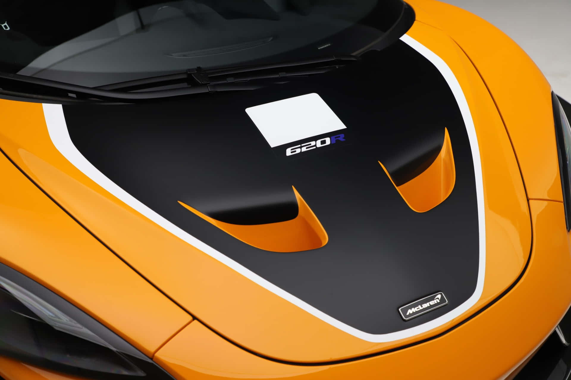 Mclaren 620r 桌布 壁紙 — 鮮橙色McLaren 620R跑車引擎蓋特寫，帶有黑色飾邊和白色賽車條紋。