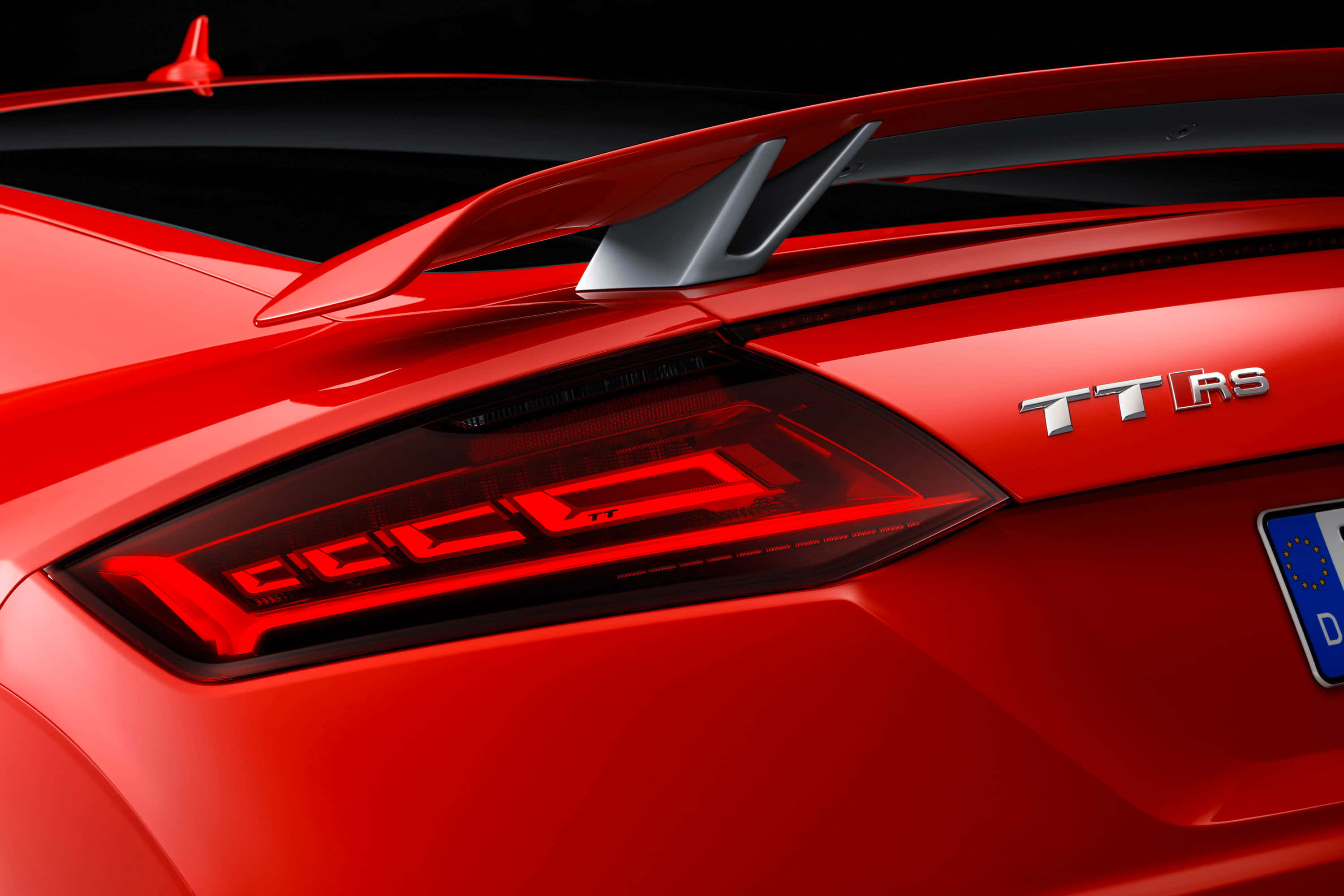 Audi Tt Rs 桌布 壁紙 — 鮮紅色奧迪TT RS車尾特寫，在深色背景下展示時尚尾燈和運動尾翼。
