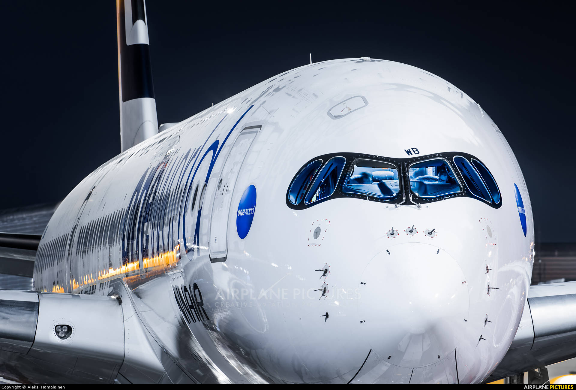 芬蘭航空駕駛艙 壁紙 — 夜晚白色空中巴士A380飛機機頭的近距離特寫，藍色駕駛艙窗戶和照亮的地面燈光反射在機身上。