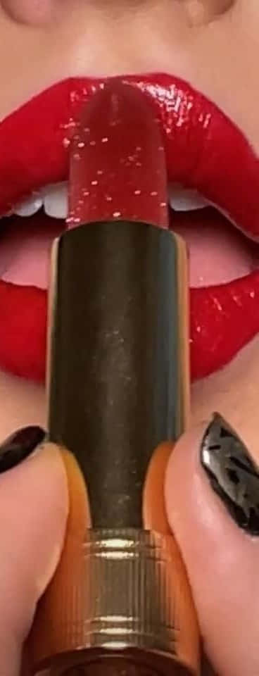 lipstick 桌布 壁紙 — 近距離拍攝的亮澤紅唇，正在用黑色圖案指甲塗抹閃爍紅色唇膏。