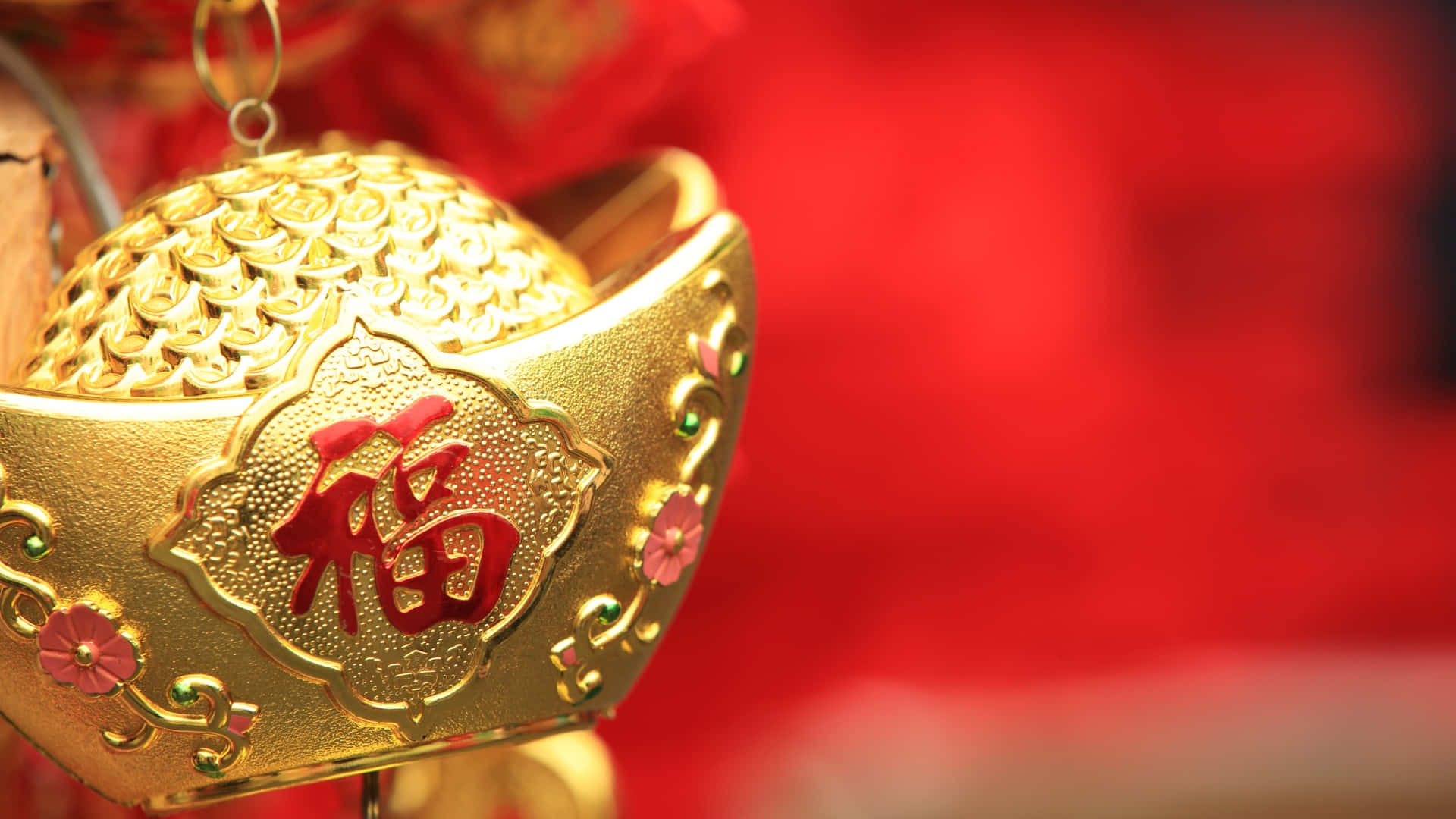  壁紙 — 金色金條裝飾的特寫，帶有紅色中文字「福」和花卉點綴，背景為模糊的紅色。