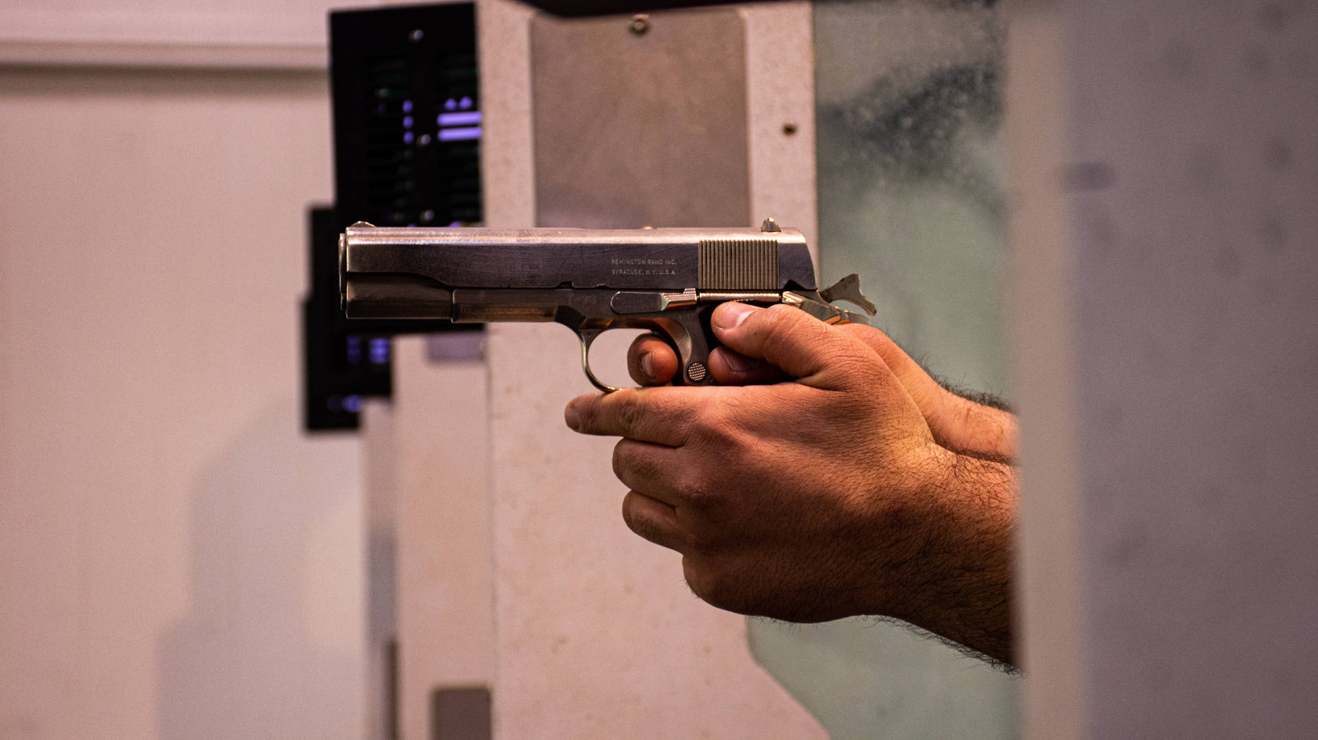 雙手握槍 壁紙 — 室內射擊場中，煙霧可見，一雙手緊握銀色手槍的特寫。