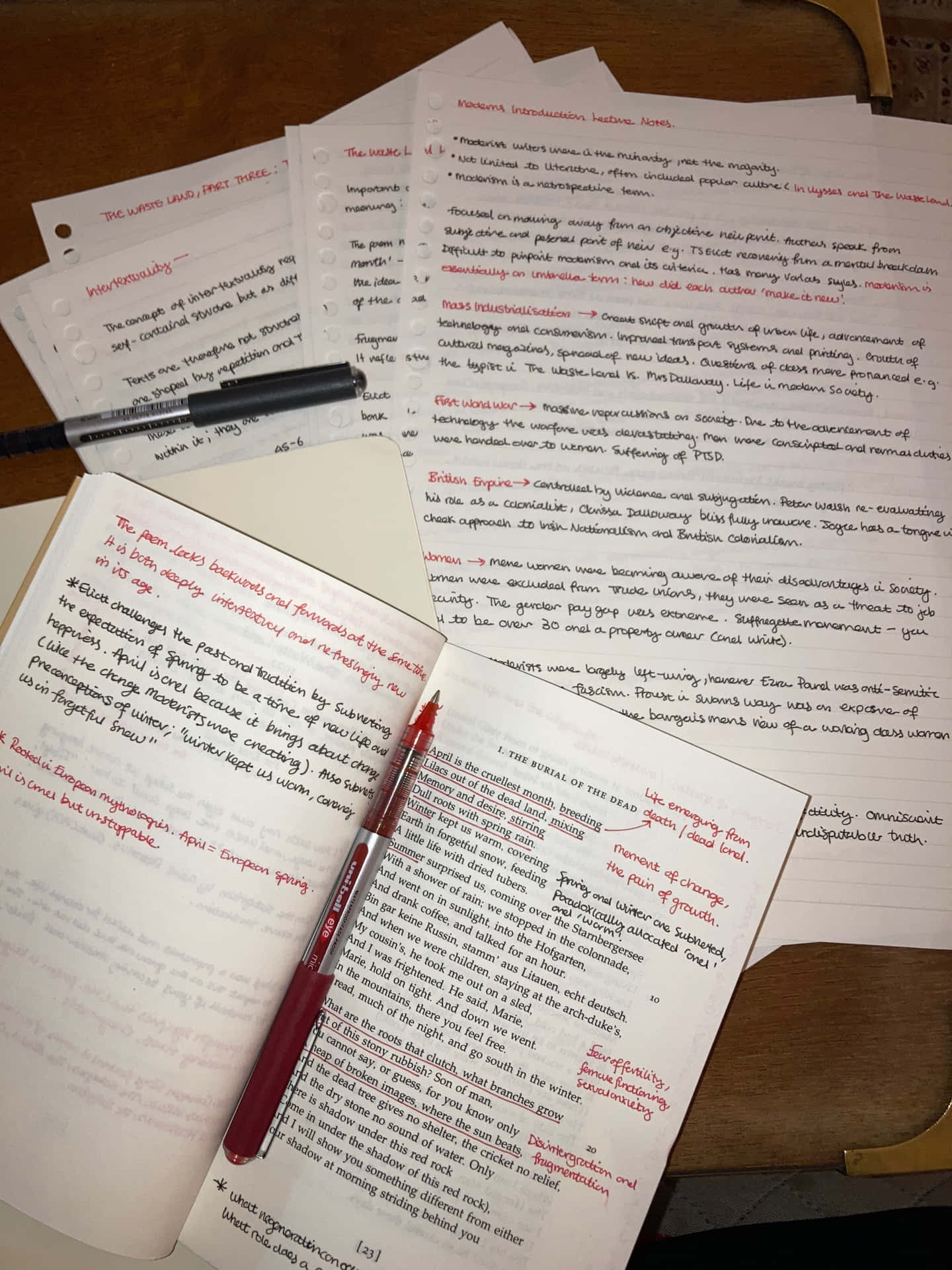  壁紙 — 木製書桌上散落著手寫筆記、打開的教科書、紅色筆和一支黑色筆的特寫。