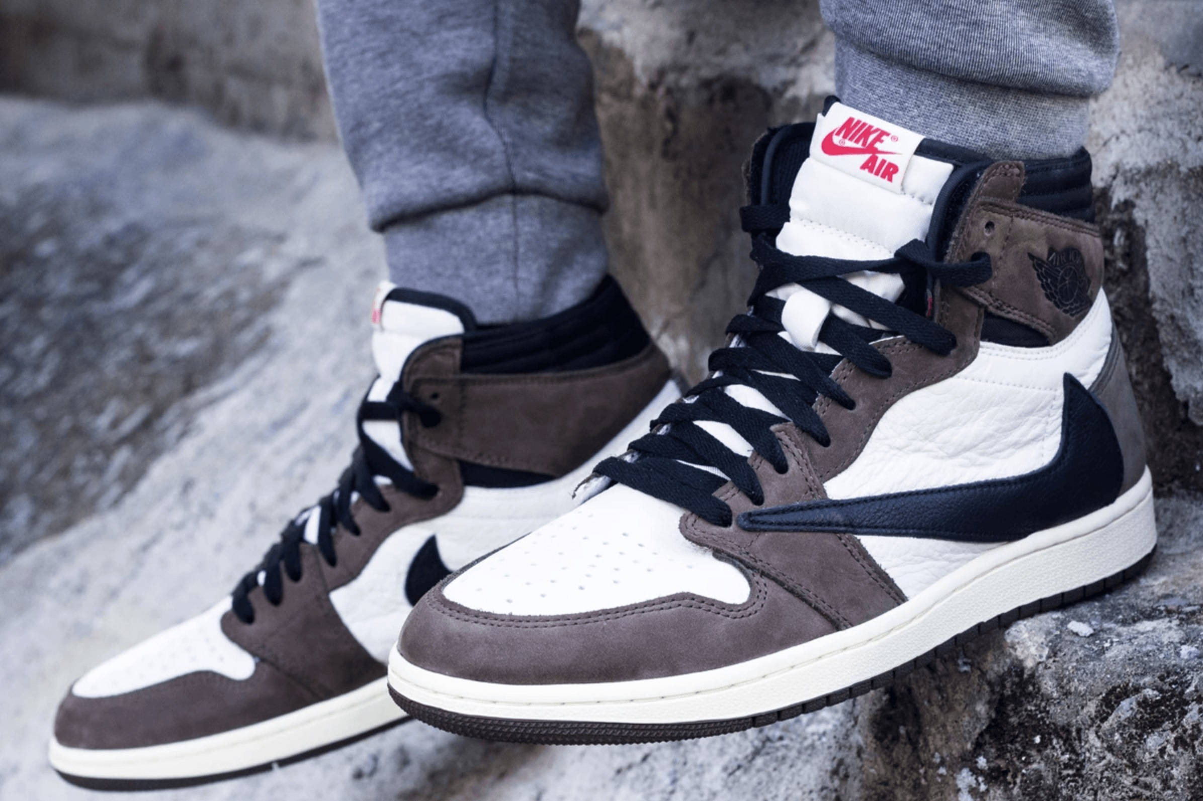 Cactus Jack Travis Scott Jordan 1 置於岩石 壁紙 — 高筒運動鞋特寫，鞋面有白色、棕色和黑色拼接，放置在紋理灰色岩石上。
