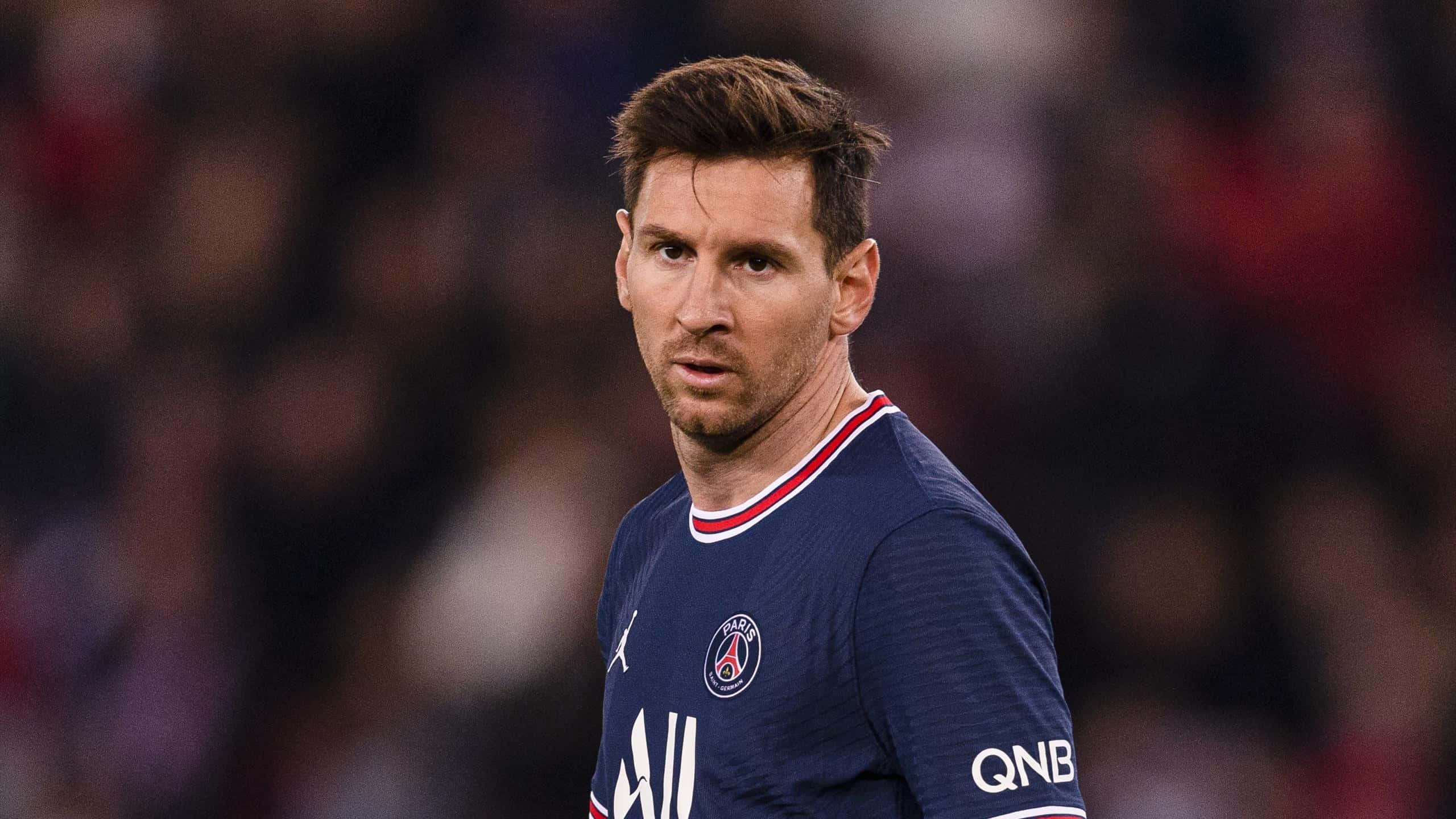 Messi 2022 桌布 壁紙 — 里奧內爾·美斯身穿巴黎聖日耳曼球衣的近距離特寫，在夜間比賽中專注地凝視。