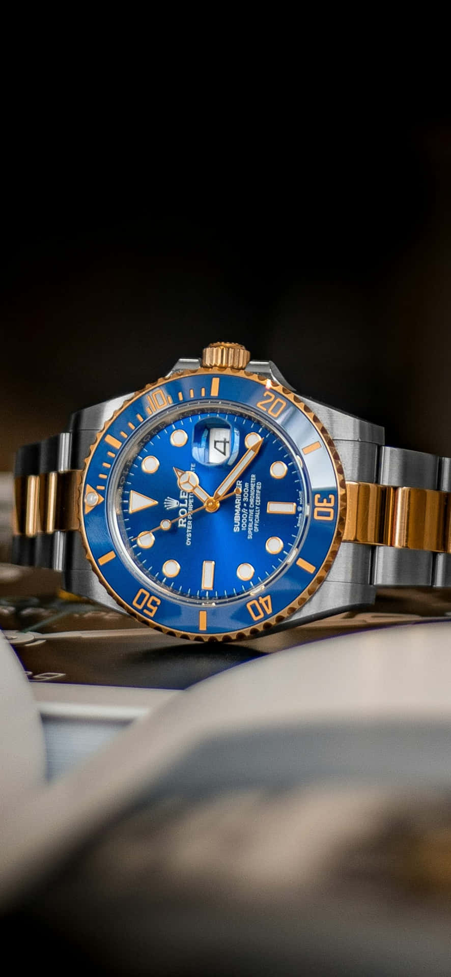  壁紙 — 豪華勞力士Submariner手錶的特寫，帶有充滿活力的藍色錶盤和金色點綴，背景為深色模糊。