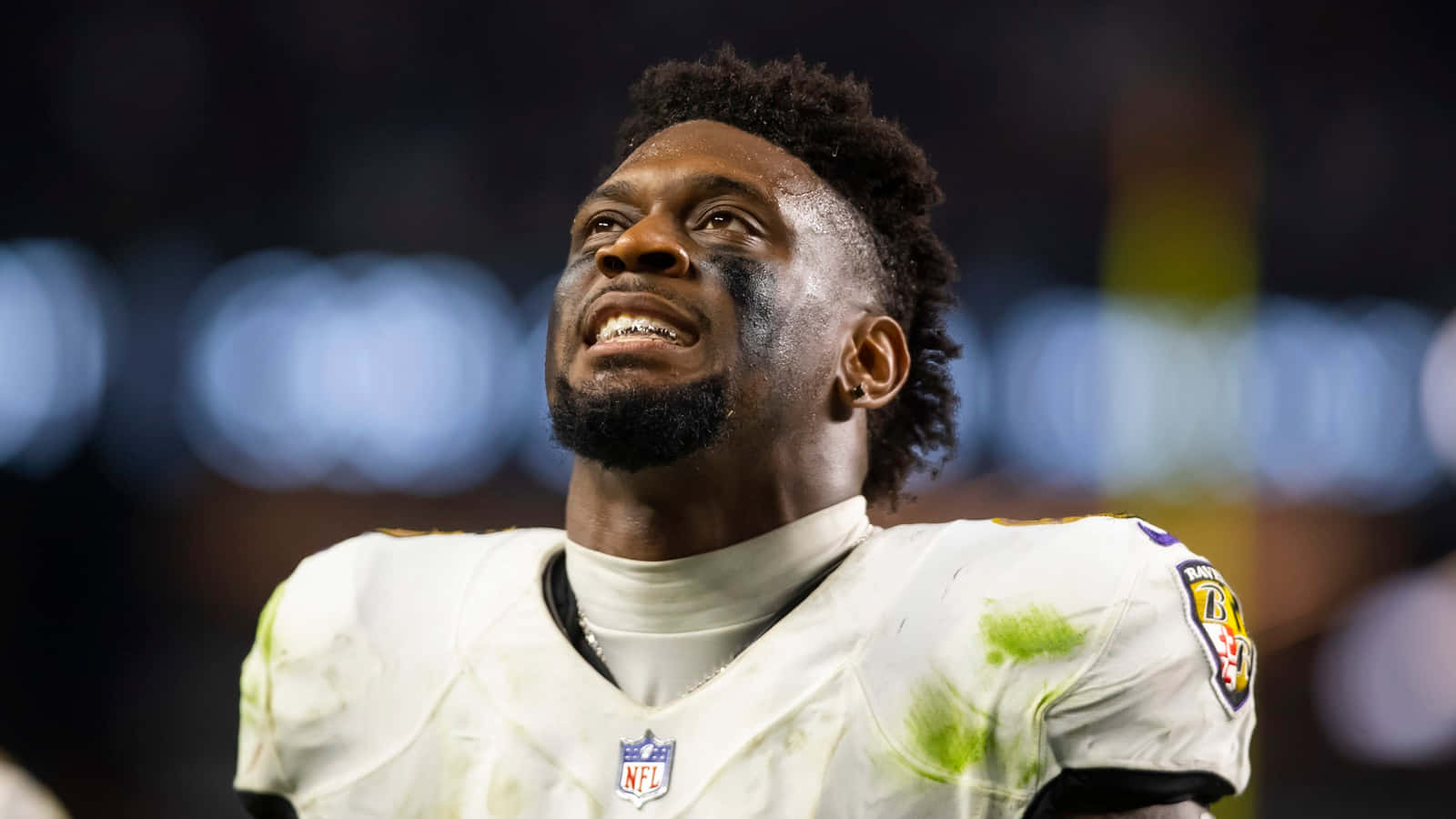  壁紙 — NFL 美式足球員面部及球衣沾有污垢，夜晚在球場向上望的特寫。