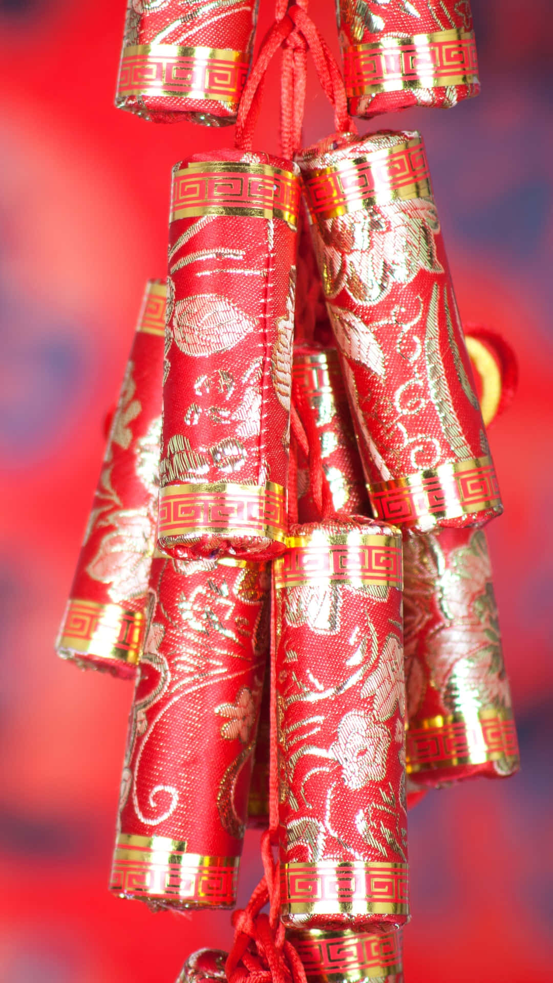  壁紙 — 特寫裝飾性紅金中國鞭炮懸掛在模糊的節日背景上。