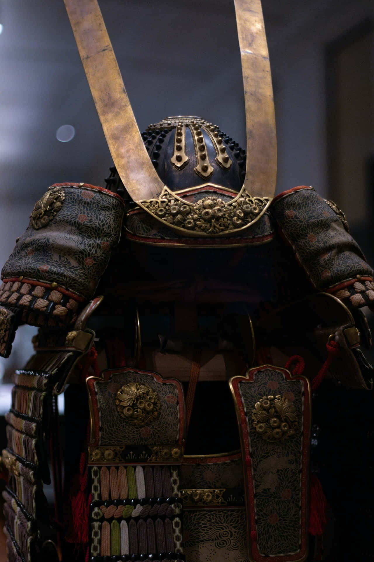  壁紙 — 在柔和嘅博物館燈光下，華麗嘅武士盔甲特寫，帶有金色點綴同深色布料。
