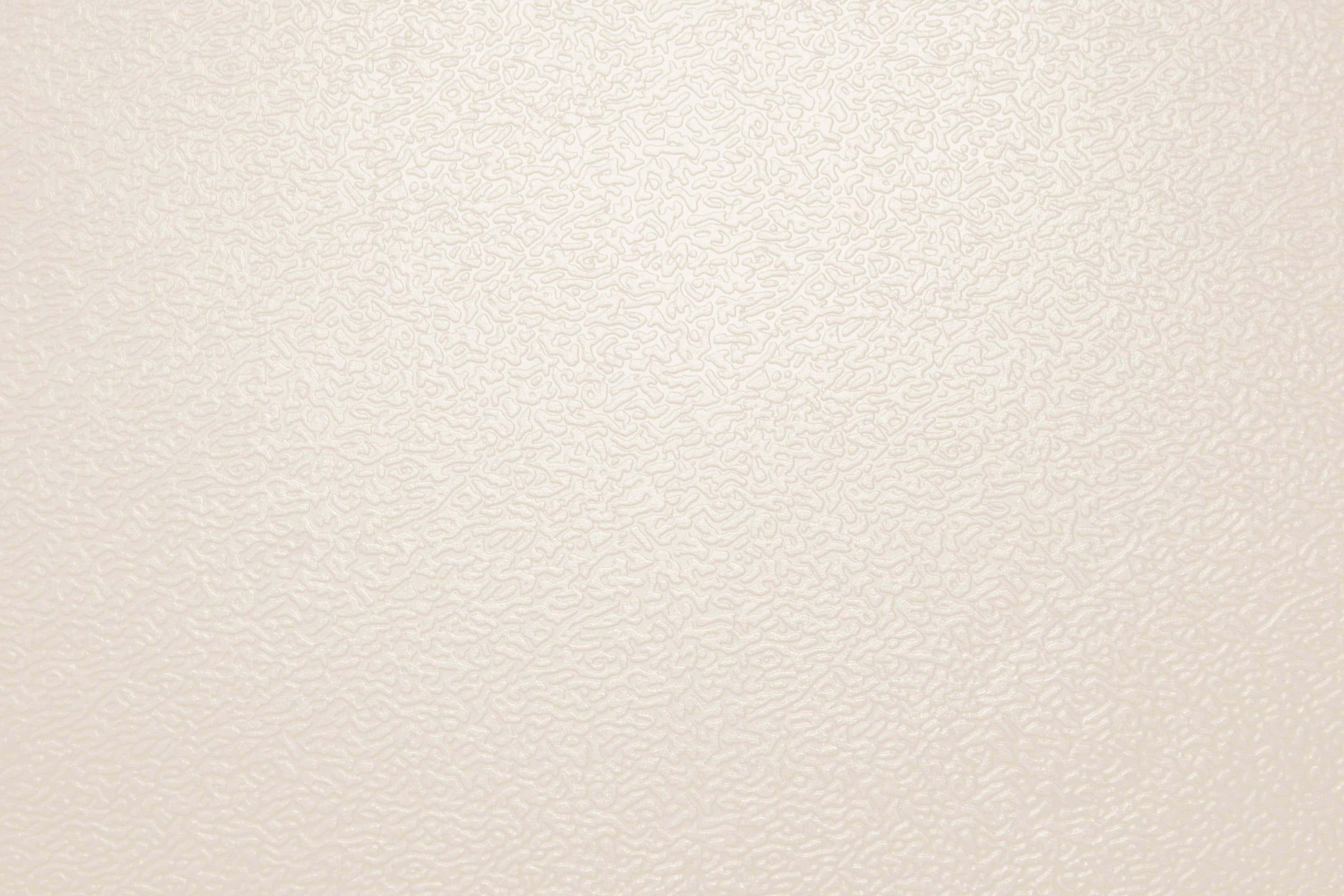 Cream Color 桌布 壁紙 — 柔和燈光下，光滑米白色紋理牆紙的特寫，帶有微妙的漩渦壓花圖案。