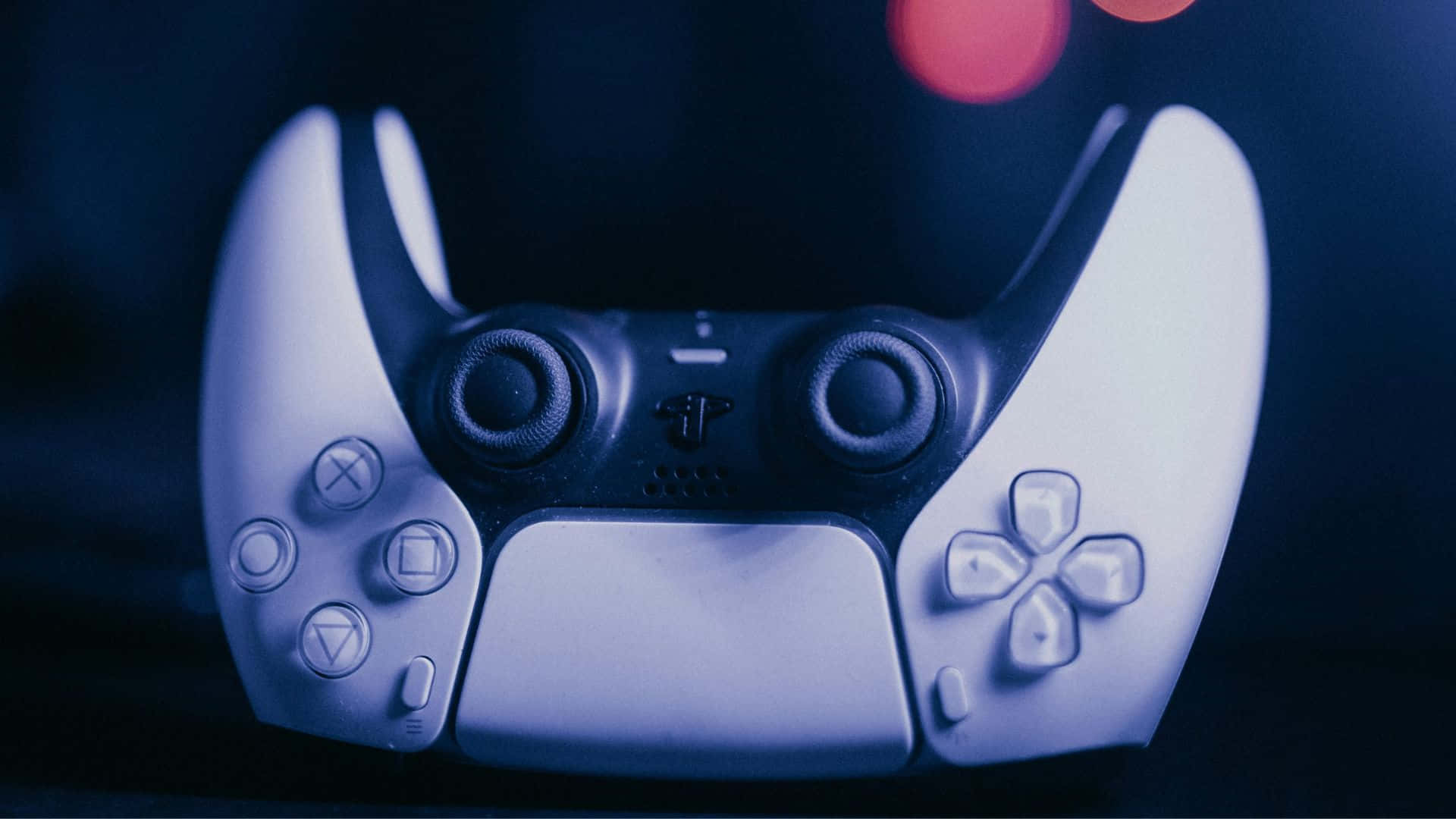  壁紙 — 白色PlayStation 5手掣嘅特寫，沐浴喺冰冷藍光之中，背景有柔和嘅紅色散景。