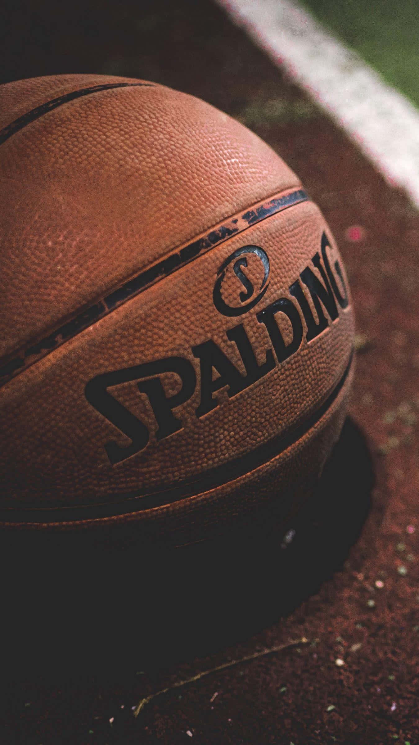 ball 桌布 壁紙 — 一個磨損的Spalding籃球特寫，放在有白色邊界線的球場上，柔和對焦。