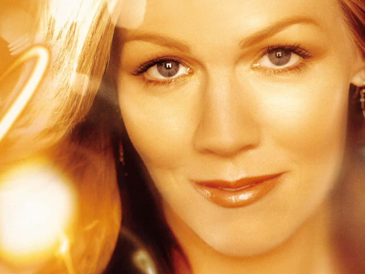 Jennie Garth 桌布 壁紙 — 一位女性的特寫肖像，帶有溫暖的金色燈光和臉部周圍柔和的散景高光。