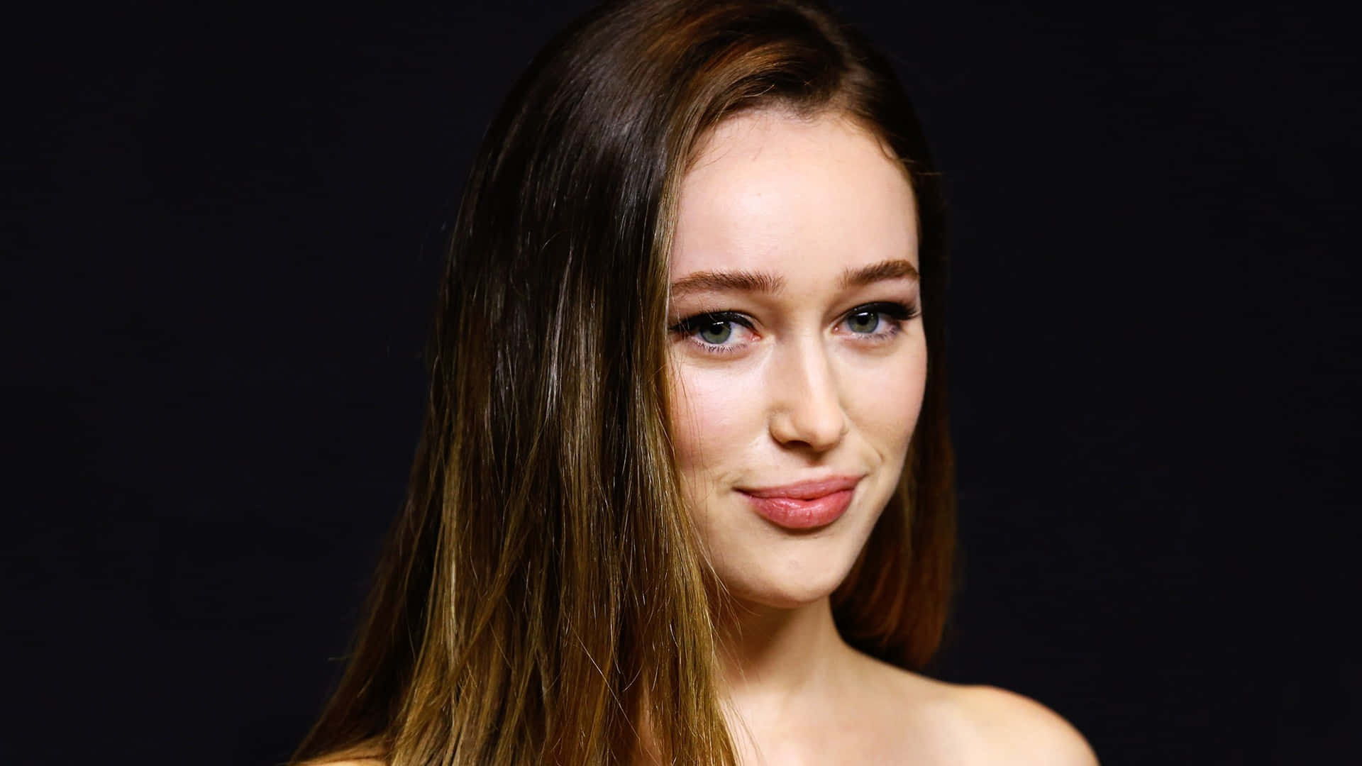 alycia debnam carey 桌布 壁紙 — 一個年輕女性的特寫肖像，長長嘅棕色頭髮同藍色眼睛，喺深色背景前溫柔微笑。