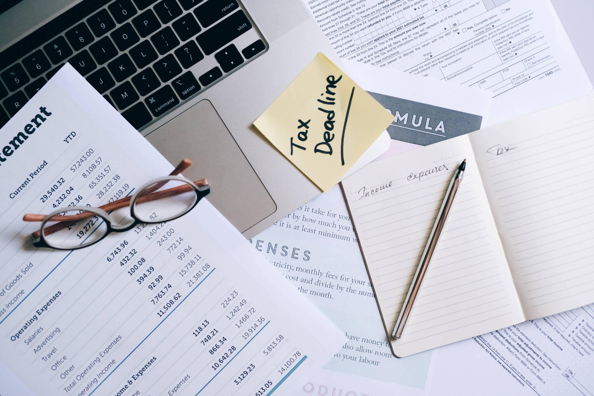 雜亂桌子上的稅務文件和一張寫著 Tax Deadline 的黃色便利貼。