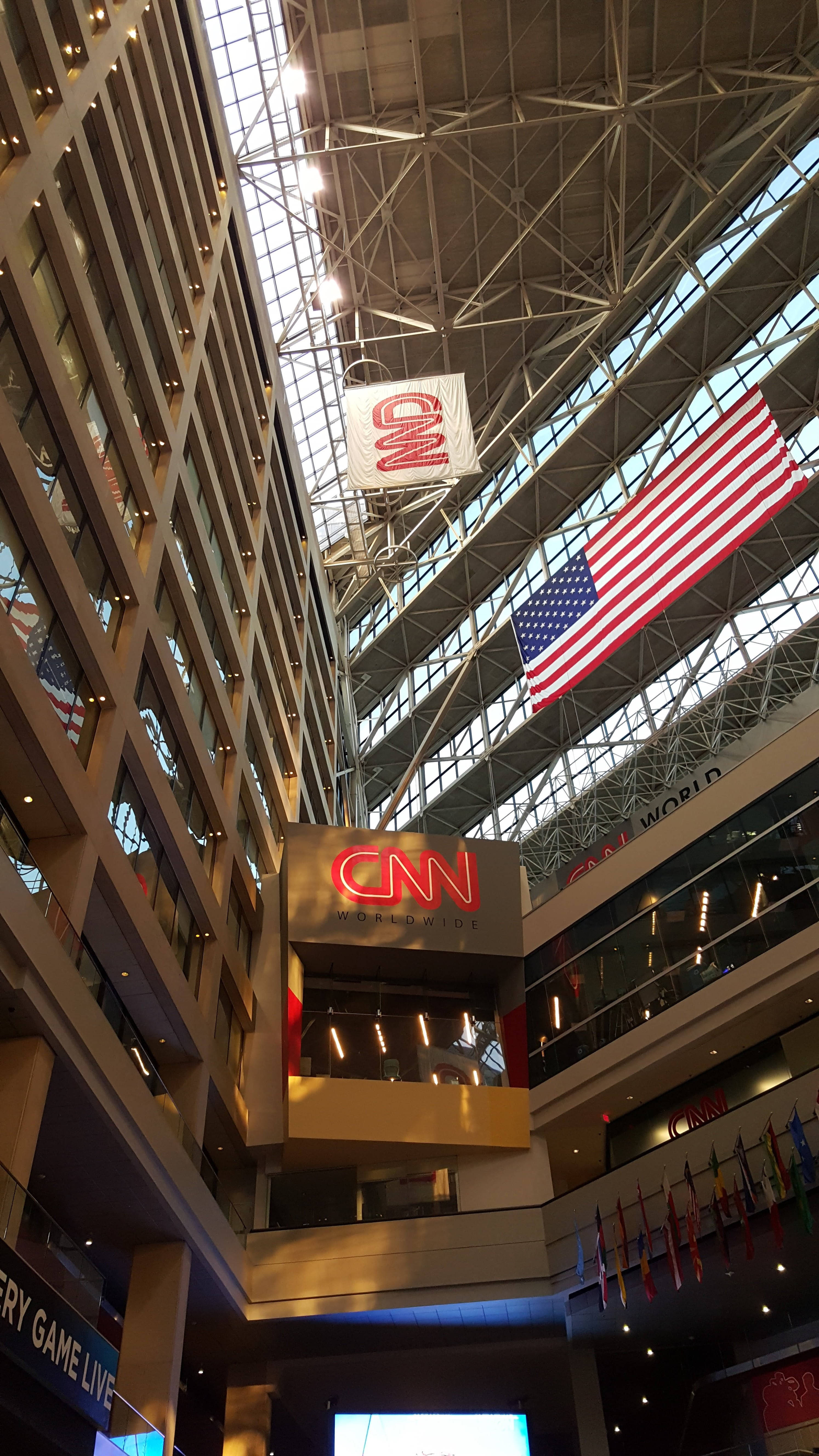 CNN 亞特蘭大大廳 壁紙 — 高聳的中庭，設有CNN Worldwide標誌和一面大型美國國旗，懸掛在玻璃和鋼製天花板上。