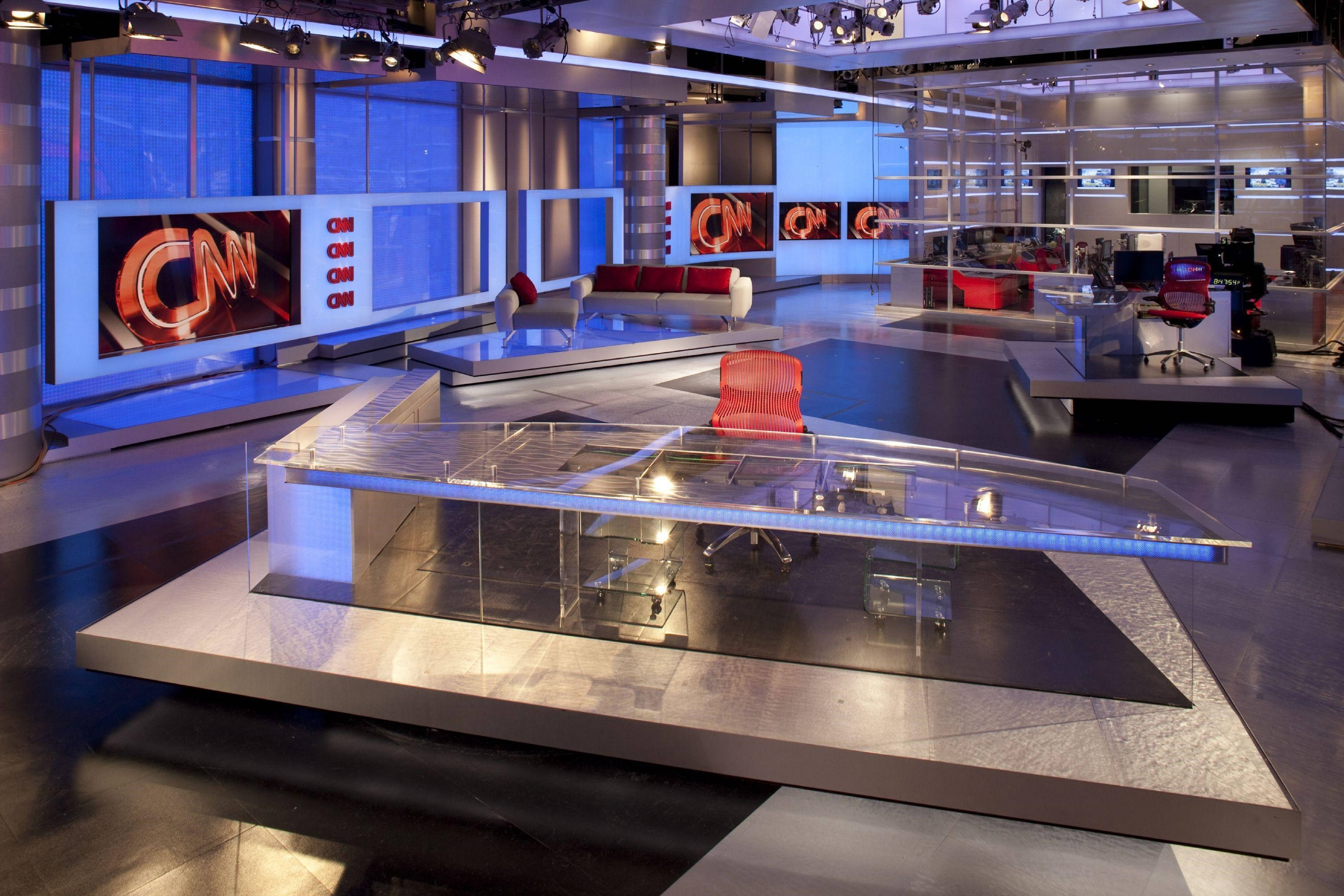 CNN 亞特蘭大新聞室 壁紙 — 一個時尚現代的CNN新聞工作室，配有玻璃桌、紅色椅子和藍色燈光，反射在拋光地板上。