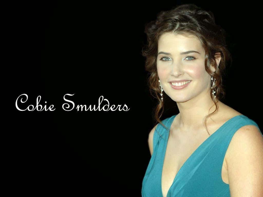 Cobie Smulders 桌布 壁紙 — Cobie Smulders 喺黑色背景前，身穿藍綠色連身裙，溫暖微笑，佢個名用白色字寫出嚟。