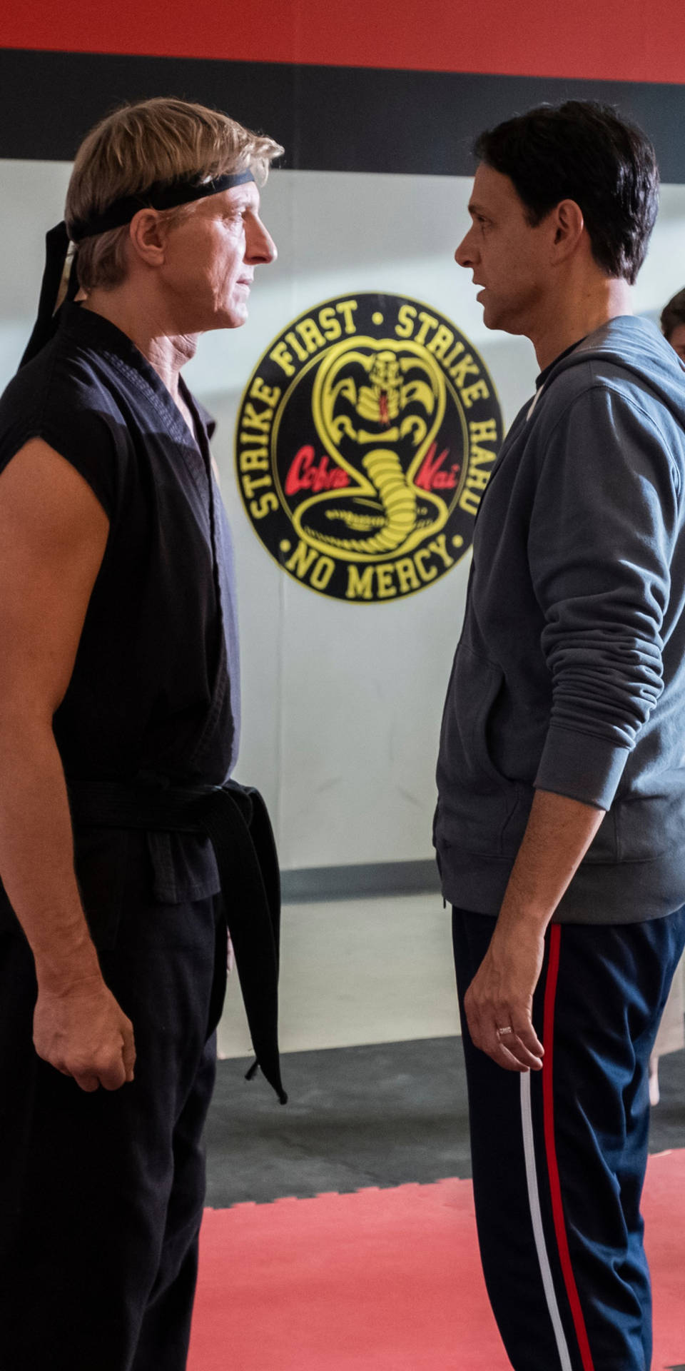 兩名武術家在道場中對峙，牆上有 Cobra Kai 標誌。