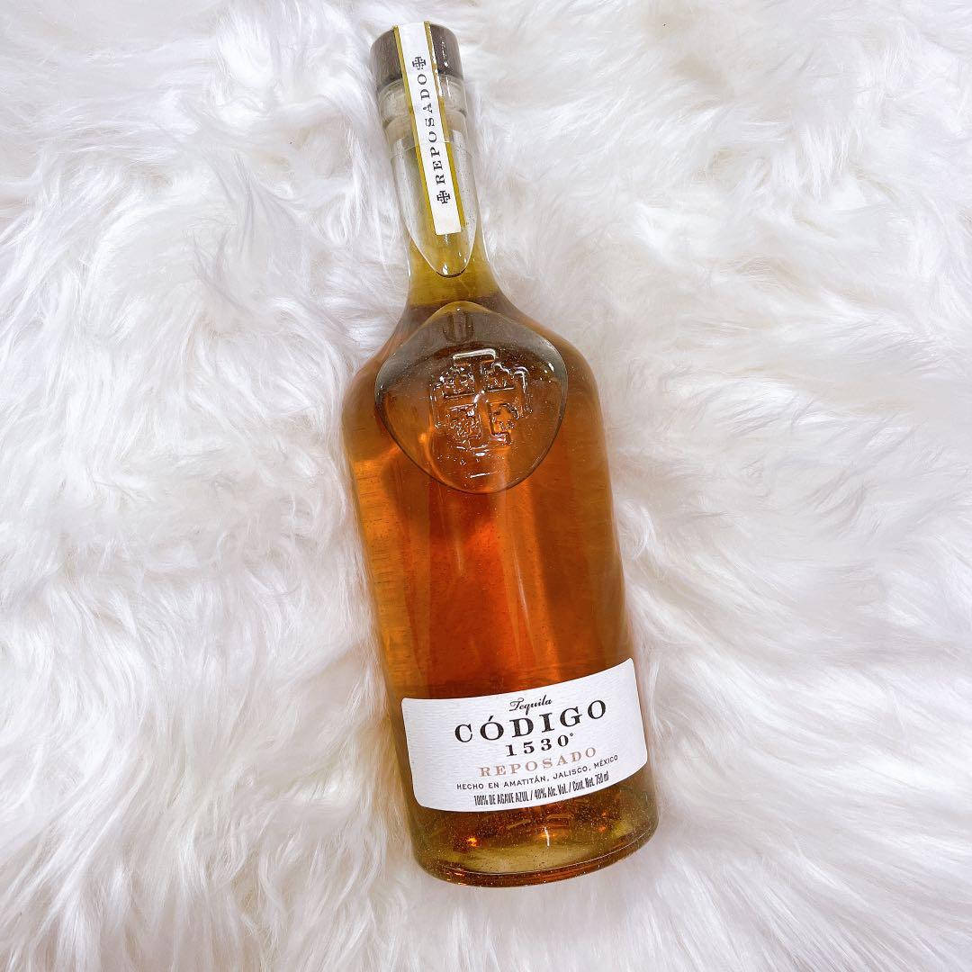 一瓶 Código 1530 Reposado 龍舌蘭酒在白色毛絨表面上。