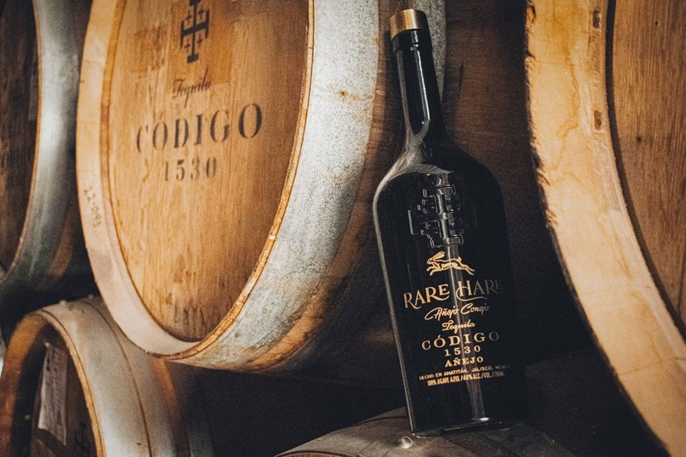 標有Rare Hare Codigo 1530的黑色龍舌蘭酒瓶靠在木桶上。