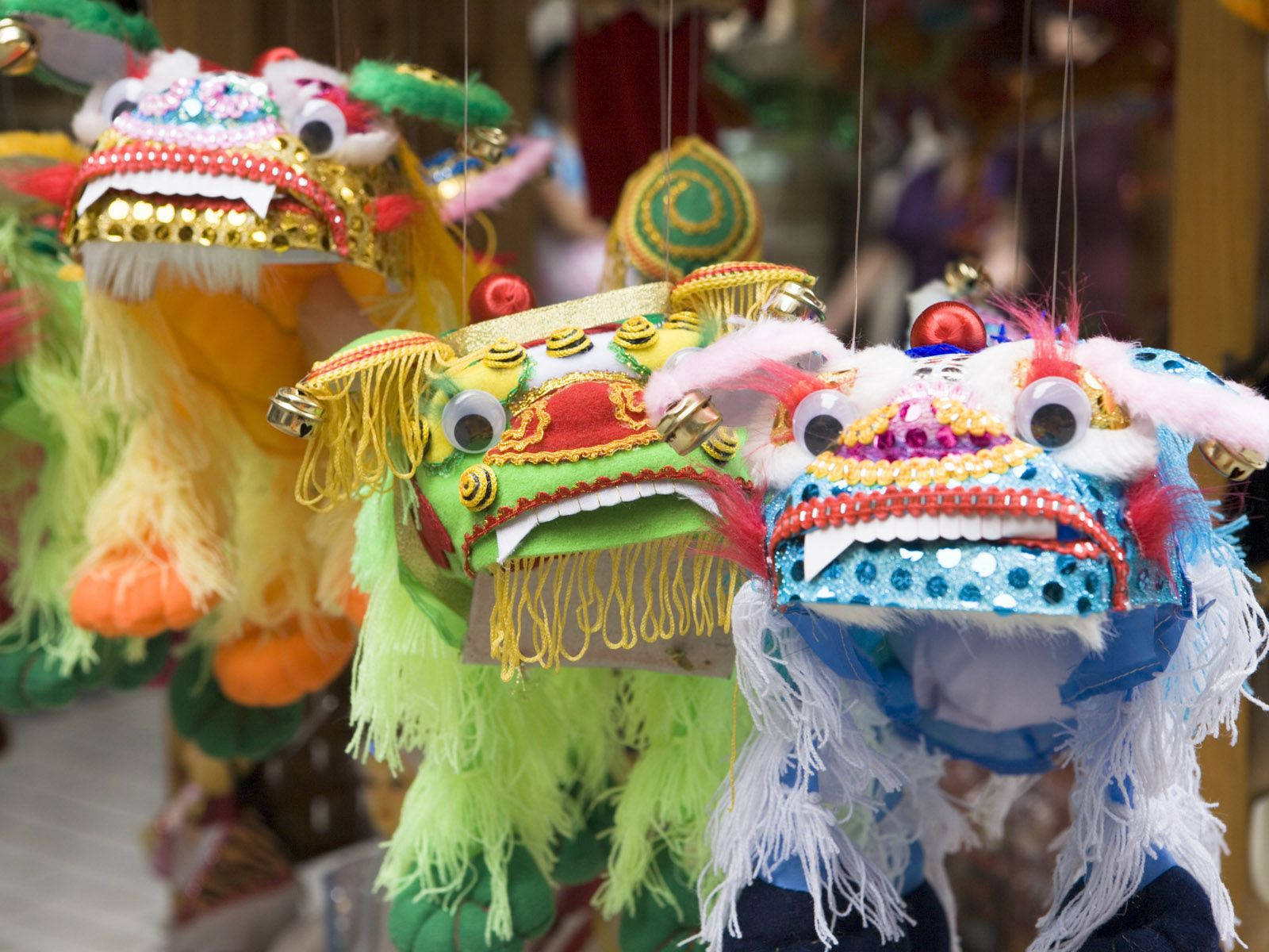充滿活力與節慶氣氛的中國新年龍舞 壁紙 — 色彩繽紛的傳統中國舞獅面具懸掛在熙熙攘攘的市場攤位中。