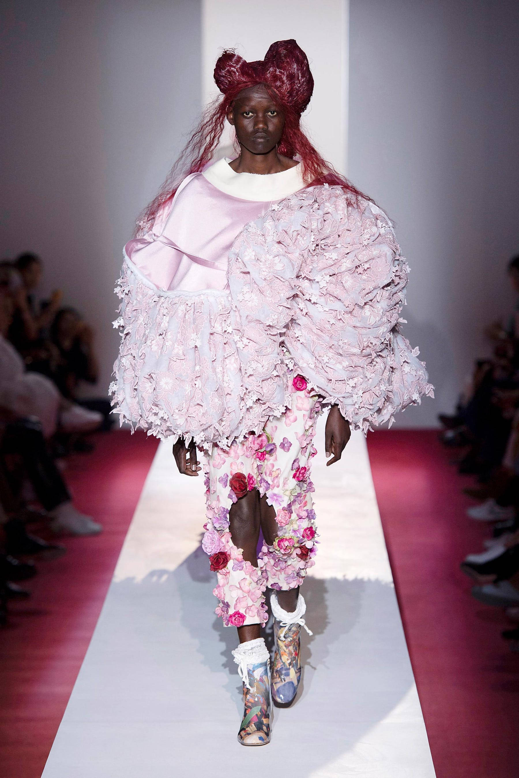 Comme Des Garçons粉紅荷葉邊上衣 壁紙 — 模特兒穿著前衛的粉紅色花卉服裝，頭上戴著一個大紅色蝴蝶結，在時裝展上走秀。
