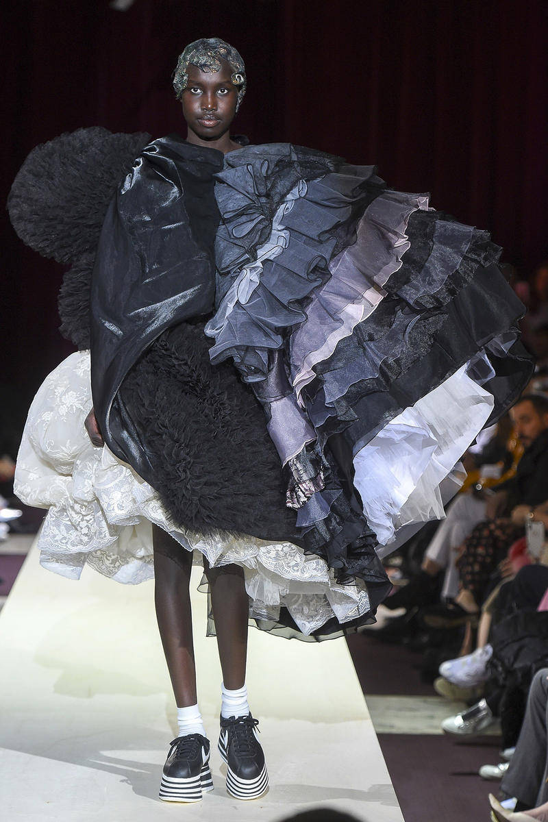 Comme Des Garçons 高級時裝荷葉邊服裝 壁紙 — 一位模特兒在時裝天橋上走秀，身穿前衛服裝，搭配層疊荷葉邊、黑色毛皮和厚底運動鞋。