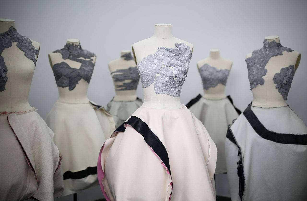 Comme Des Garçons 人偶展示連衣裙 壁紙 — 人體模型展示前衛連衣裙，採用質感灰色緊身胸衣和流暢的奶油色裙子，並以黑色和粉紅色飾邊點綴。