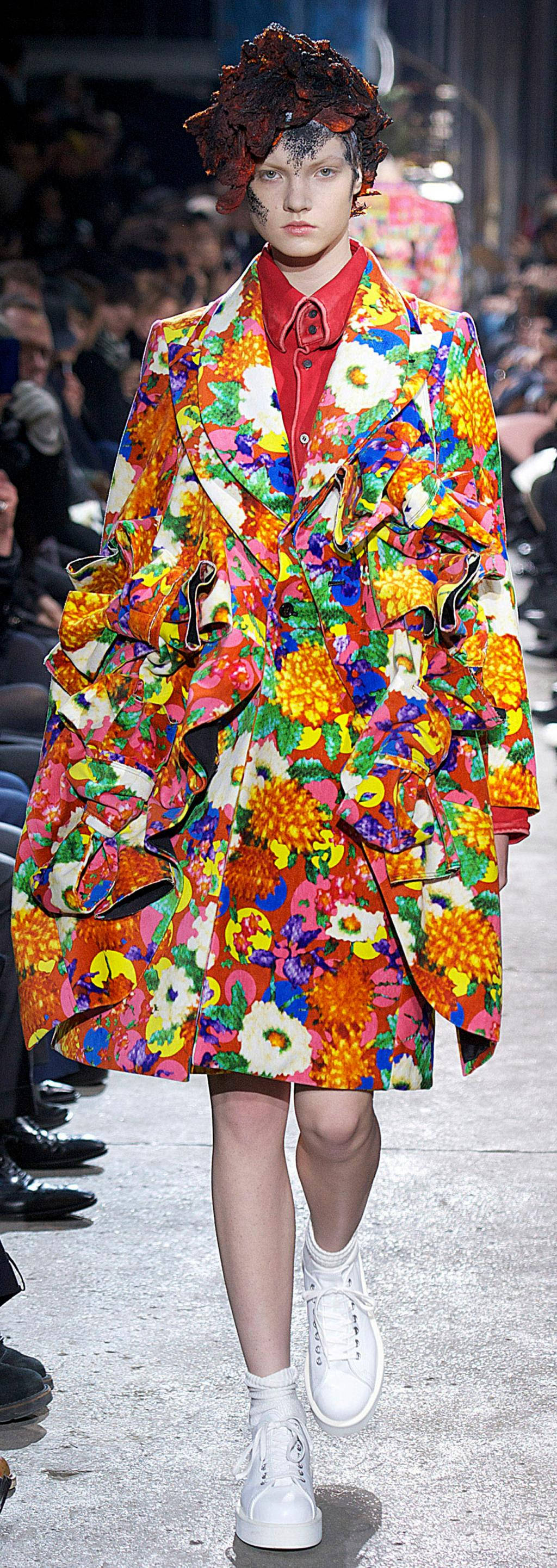 Comme Des Garçons 色彩繽紛花卉造型服裝 壁紙 — 一位模特兒穿著充滿活力的超大花卉外套，帶有鮮豔色彩和荷葉邊細節，在時裝天橋上走秀。
