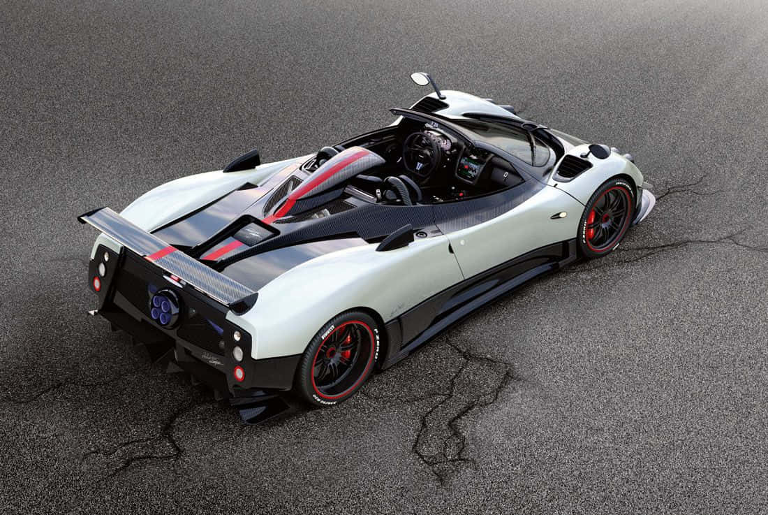 Pagani Zonda Tricolore 桌布 壁紙 — 從高角度拍攝一輛白色和黑色的帕加尼Zonda，帶有紅色點綴，停在裂開的瀝青路上。
