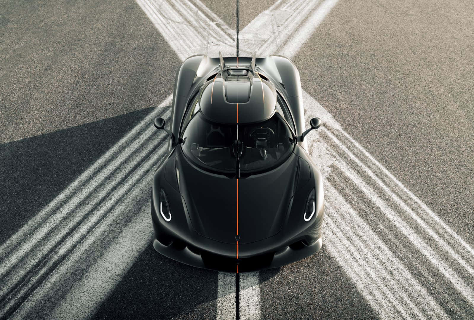  壁紙 — 從上方俯瞰，一輛時尚的黑色 Koenigsegg 超跑在賽道上，白色輪胎痕跡向外輻射。