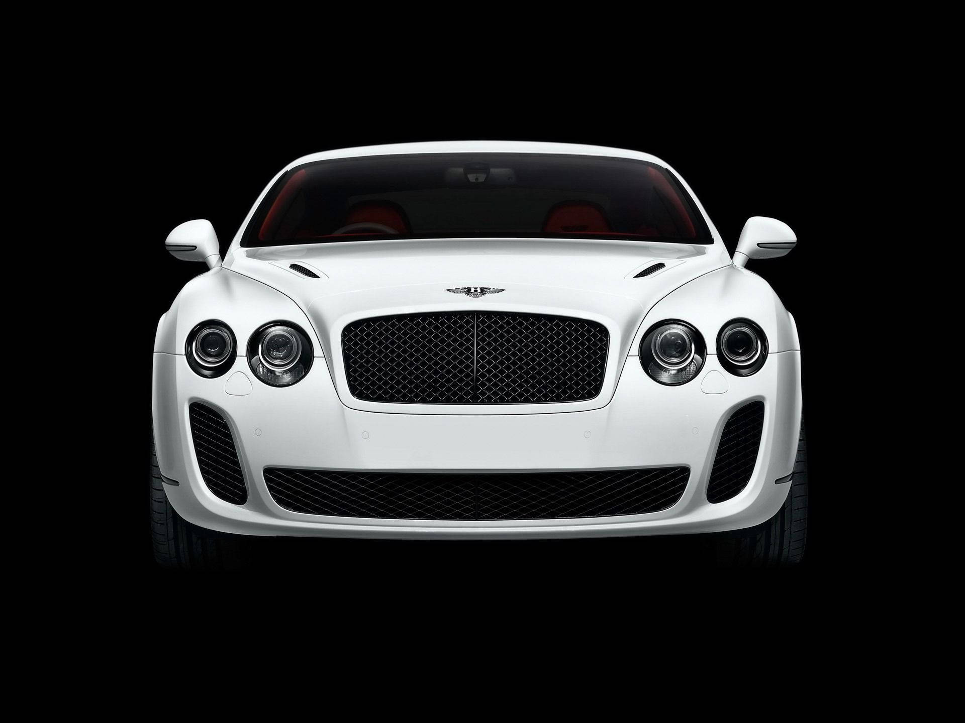 尊貴白色賓利Continental Supersports 壁紙 — 一輛純白色的賓利 Continental Supersports 在純黑背景前正面朝前，其標誌性格柵和圓形頭燈在攝影棚燈光下閃閃發光。