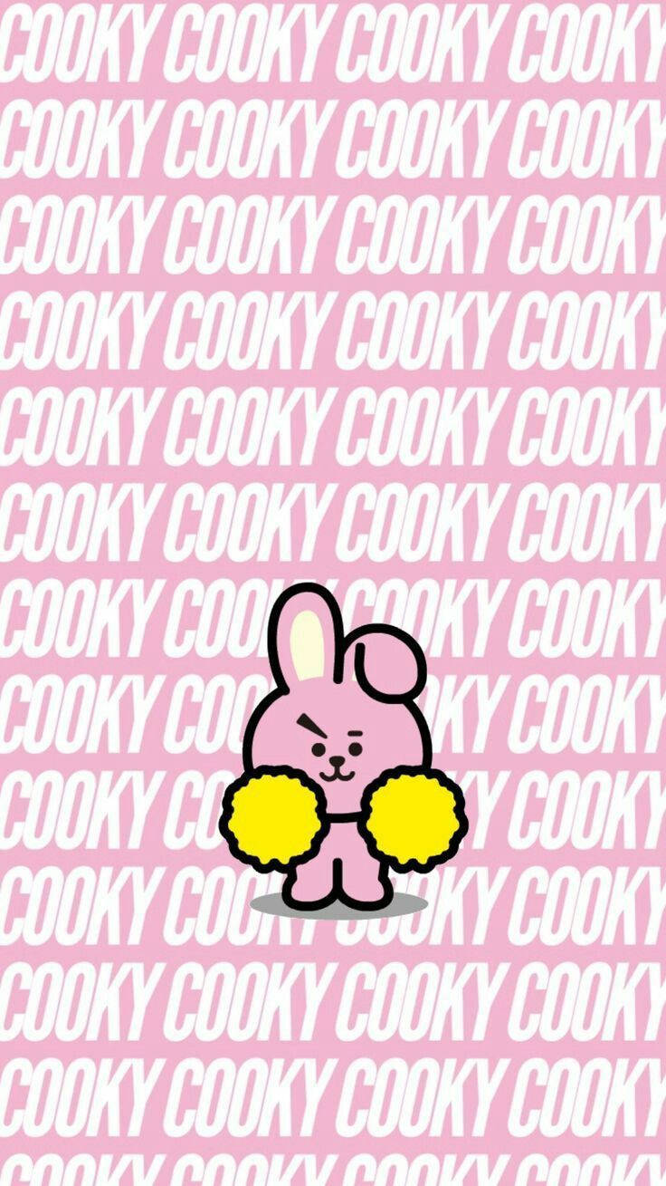 Cooky BT21 拿黃色絨球 壁紙 — 一隻粉紅色卡通兔仔拿著黃色絨球，站在重複的粉紅和白色 'COOKY' 文字背景前。