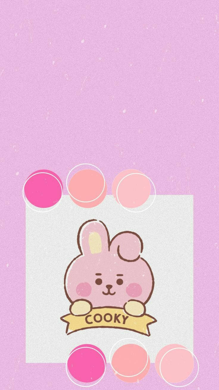 Cooky BT21 黃色絲帶 壁紙 — 一隻可愛的粉紅色卡通兔子拿著寫有 cooky 的橫幅，背景是柔和的薰衣草色和漂浮的粉彩圓圈。