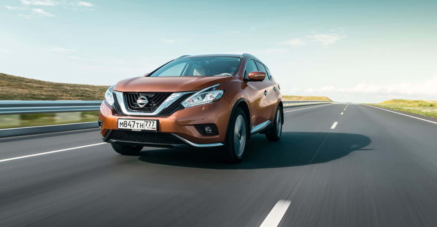 Nissan Murano 桌布 壁紙 — 一輛銅色日產Rogue SUV在陽光明媚的高速公路上行駛，帶有模糊的動感和清澈的藍天。