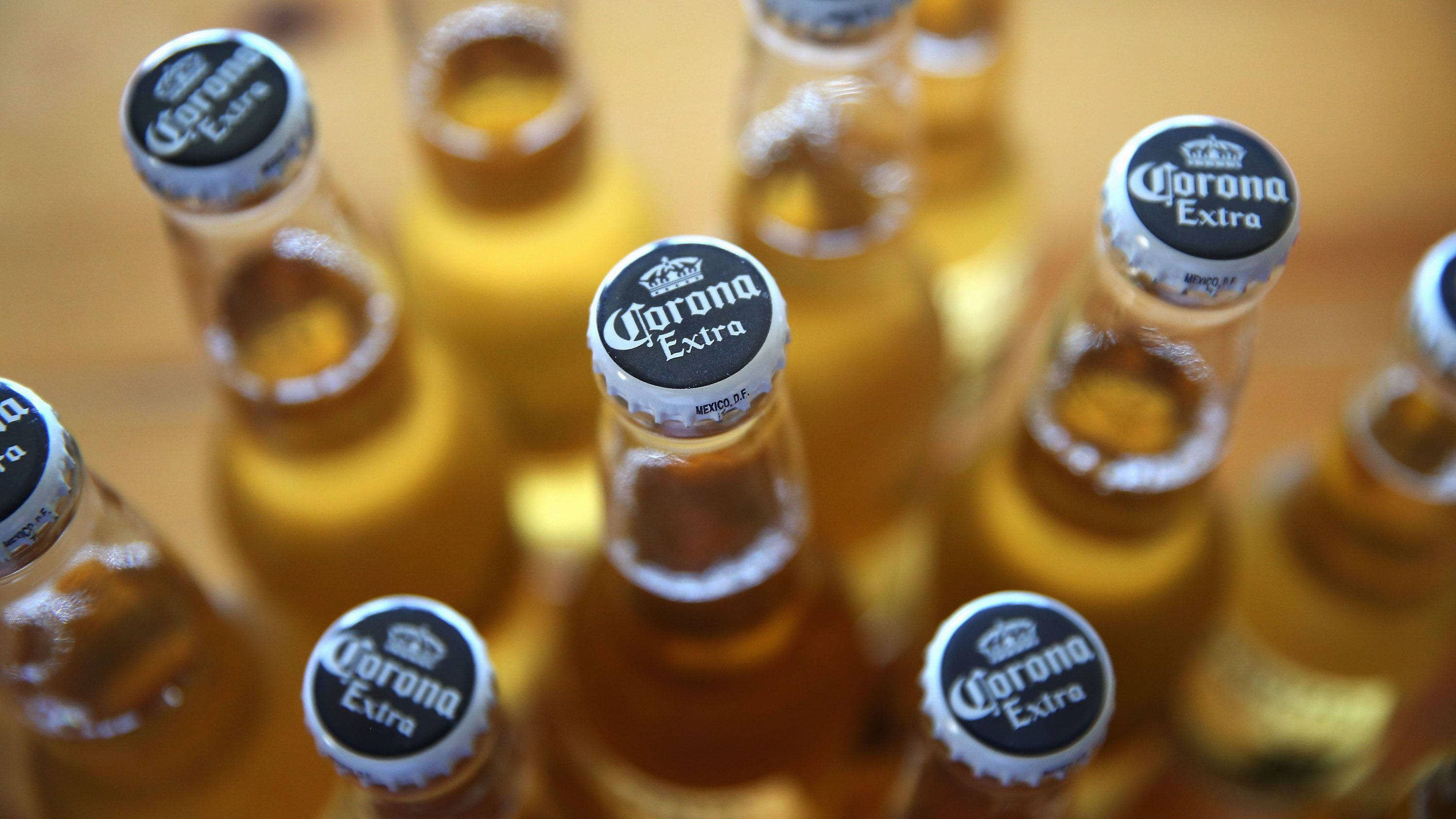 Corona Extra 啤酒瓶蓋 壁紙 — Corona Extra 啤酒瓶銀色瓶蓋特寫，排列在木質表面上。