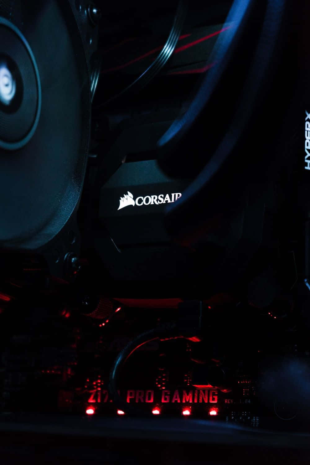 Corsair 電子遊戲設置圖片 壁紙 — 近距離拍攝遊戲電腦內部，紅色LED燈在黑暗中照亮Corsair和HyperX組件。