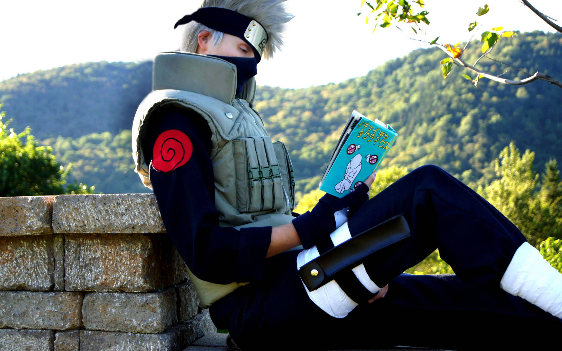 cosplay 卡卡西閱讀漫畫 壁紙 — 一位穿著精細忍者服裝的角色扮演者，在森林山坡的石牆上放鬆閱讀漫畫。