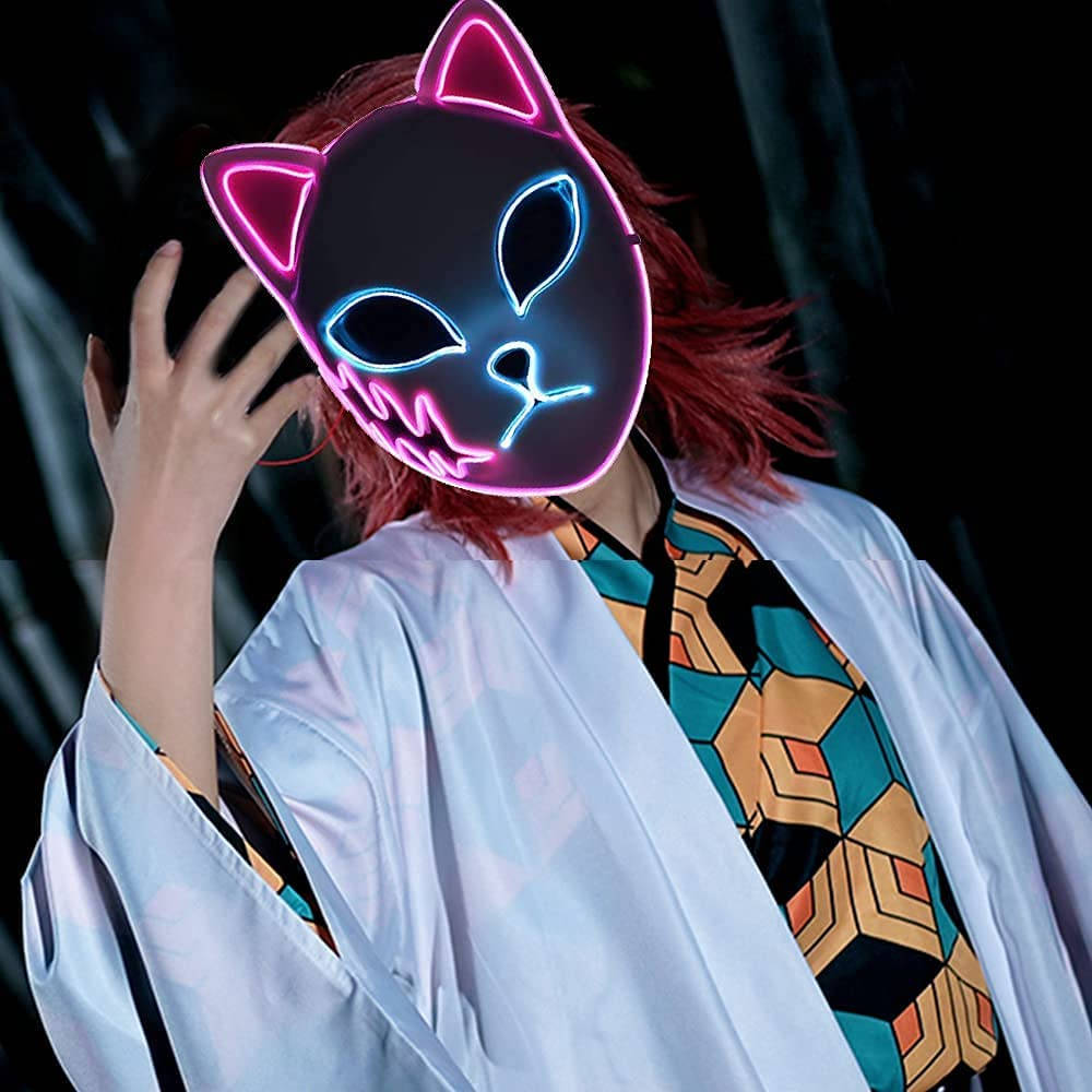 cosplayer佩戴鬼滅之刃面具 壁紙 — 一個紅髮的人戴著發光的粉紅色和藍色霓虹貓面具，在黑暗的背景前調整它。